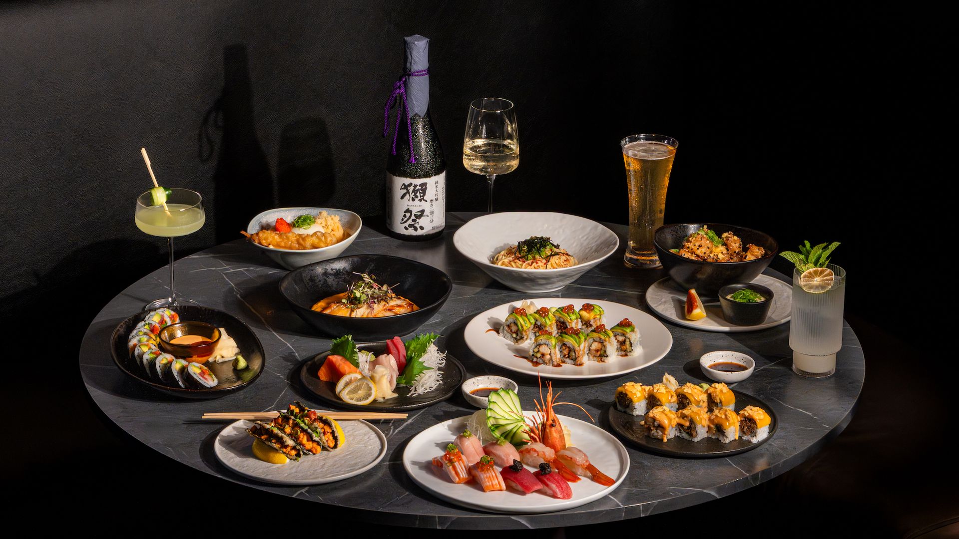 A table filled with sushi, cooked Japanese dishes and sake
