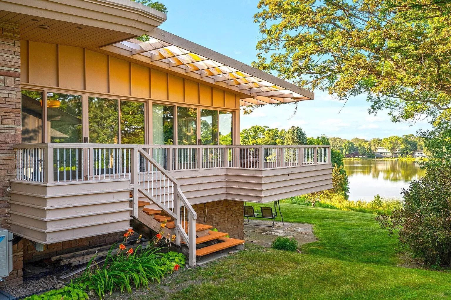 The side of a one-story house with large windows and a back deck.