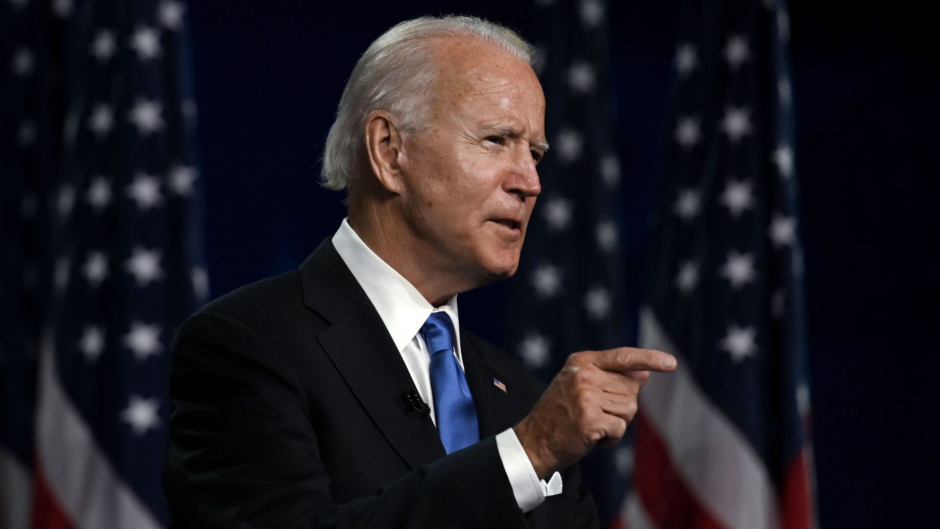 Biden speaks with American flags behind him 