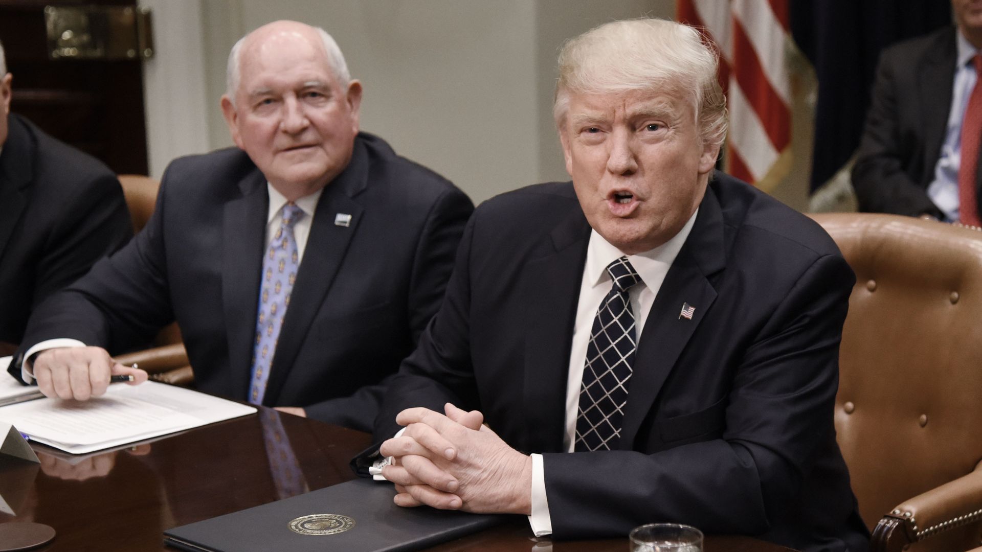 US President Donald speaks as Agriculture Secretary Sonny Perdue looks on during a roundtable with farmers in the Roosevelt Room of the White House on April 25, 2017 in Washington, DC.