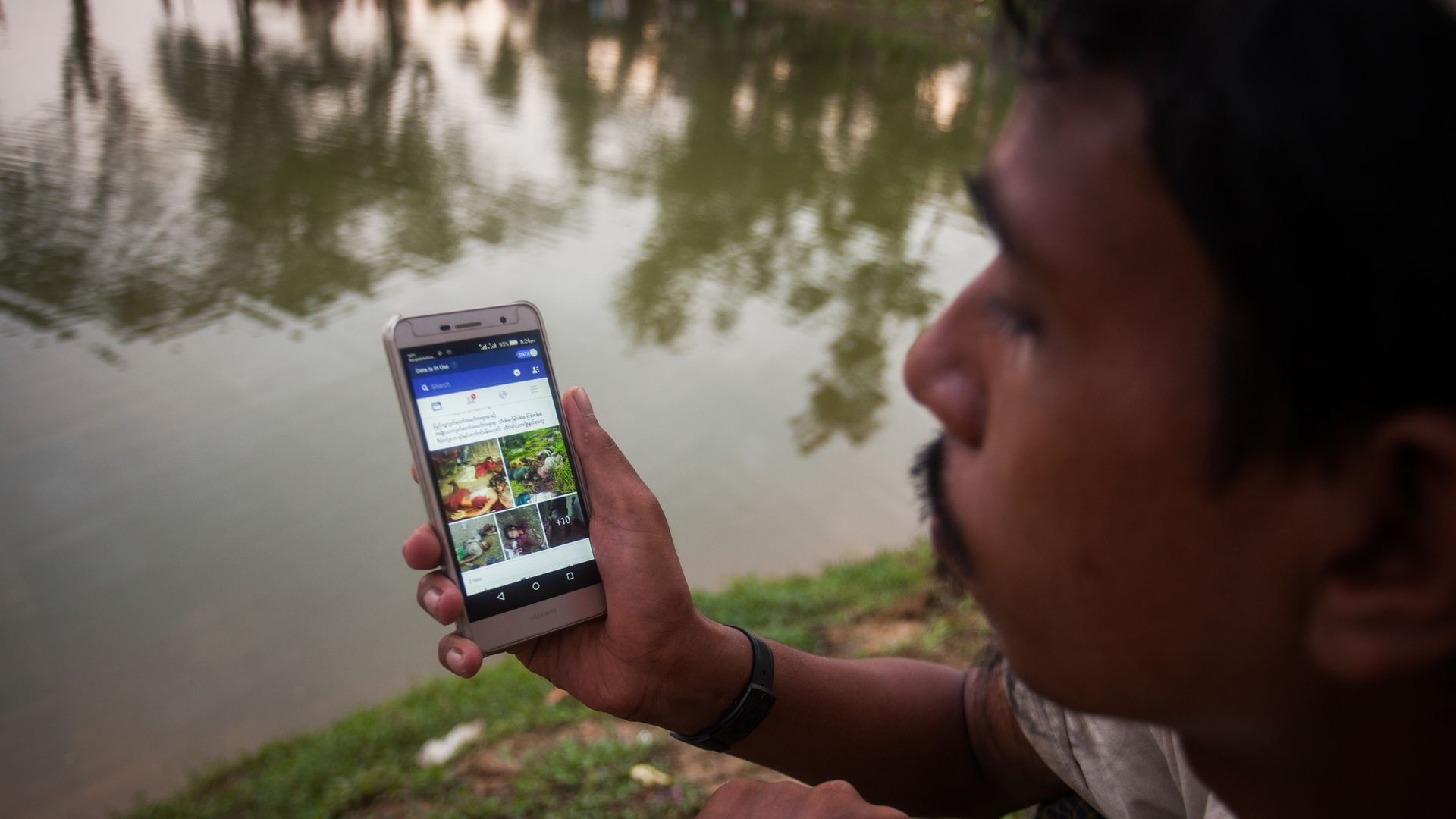 Rohingya man looking at Facebook on his phone