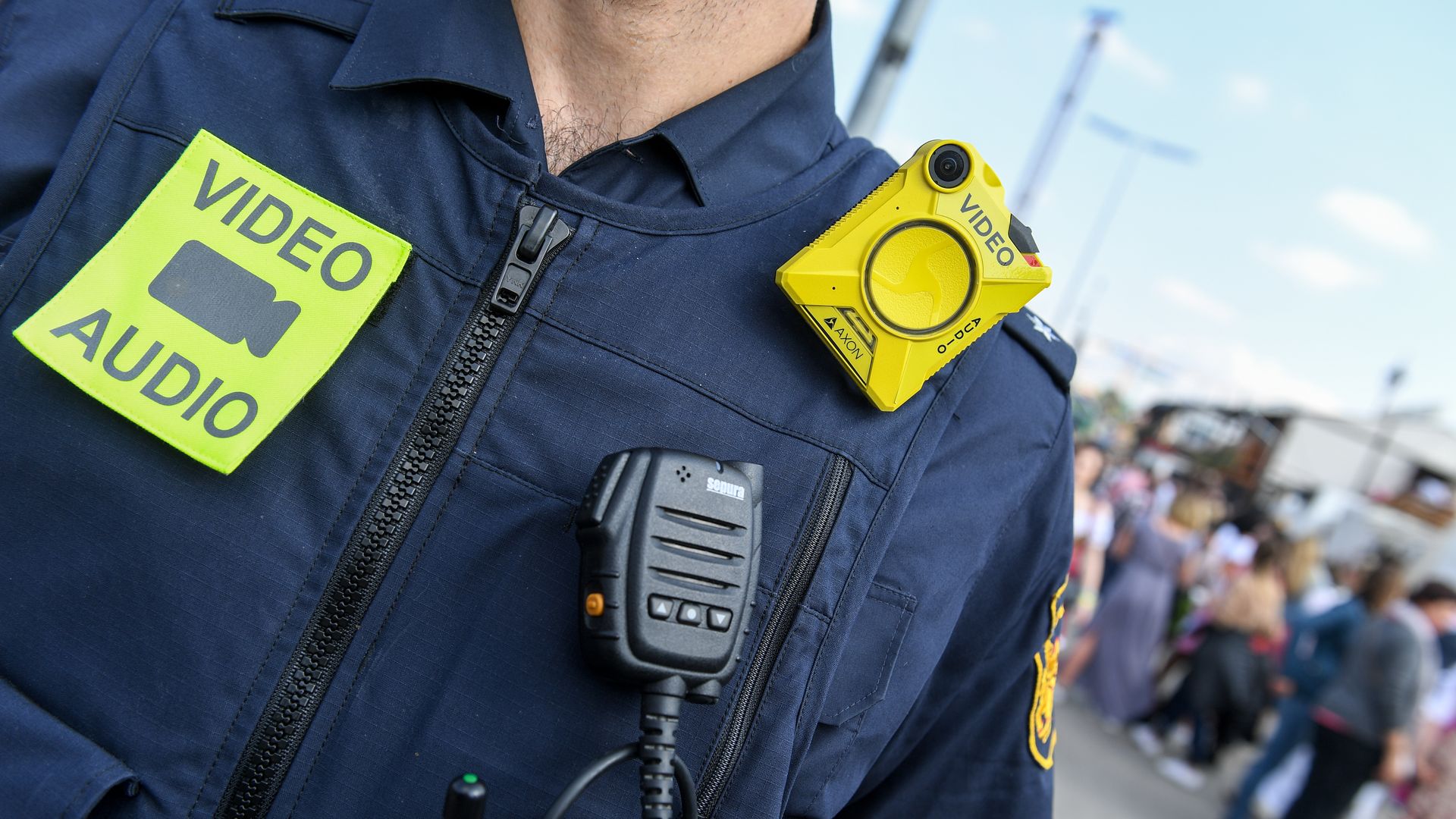 Photo of a police officer wearing a body camera and a badge that says "video/audio"