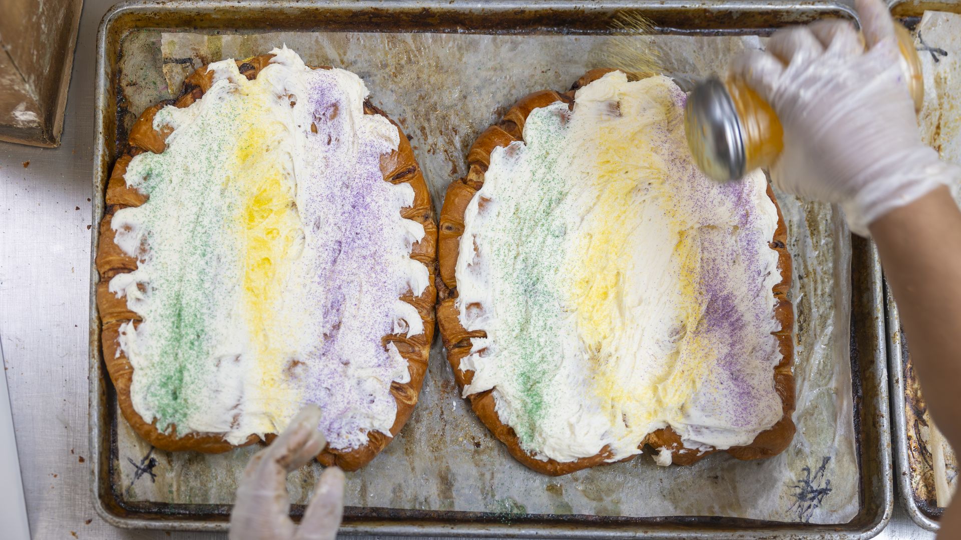 Two king cakes with green, yellow and purple sprinkles.