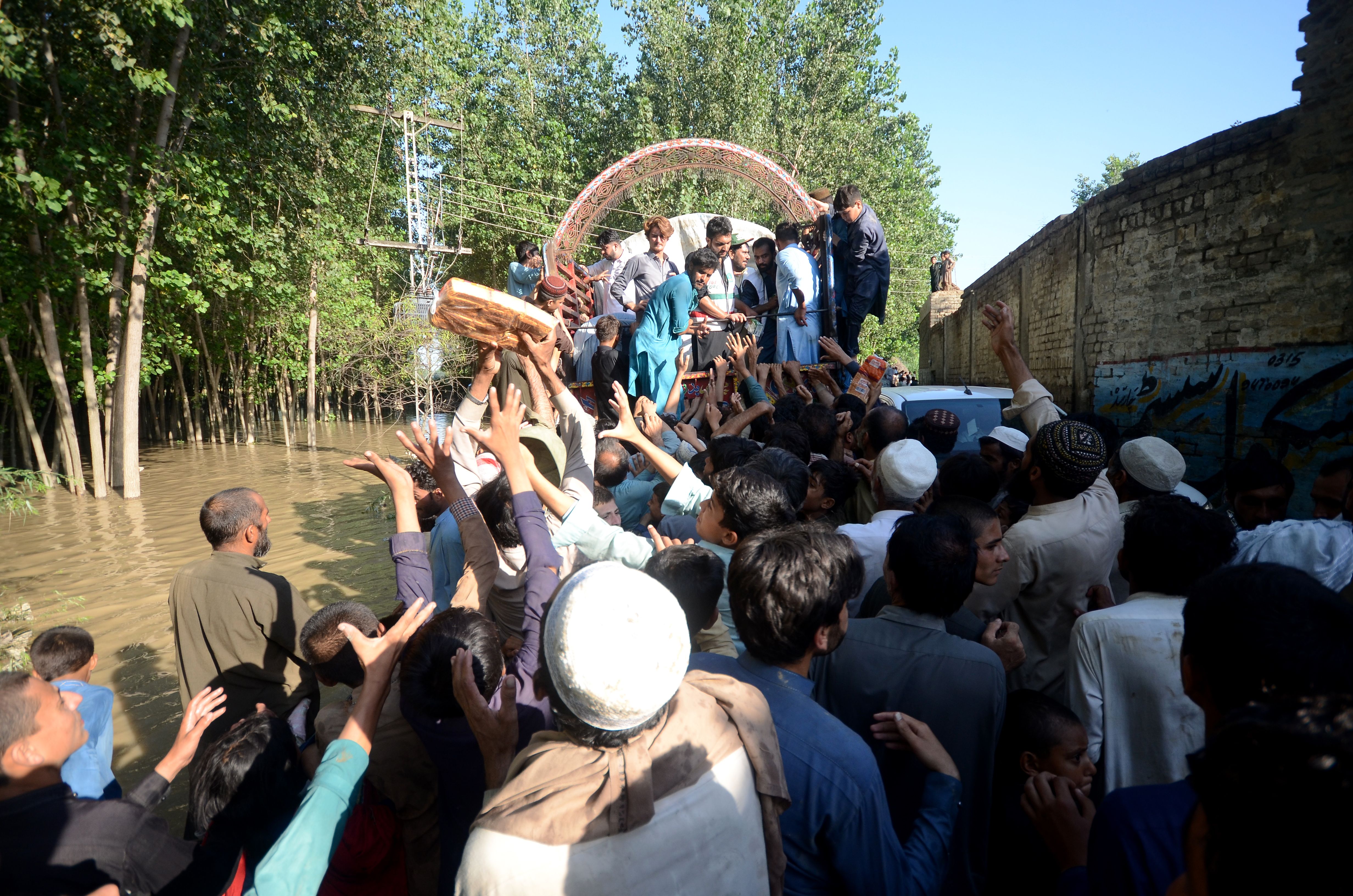 Displaced people receive food aid at a flooded area in Charsadda, Khyber Pakhtunkhwa province, Pakistan on August 28.