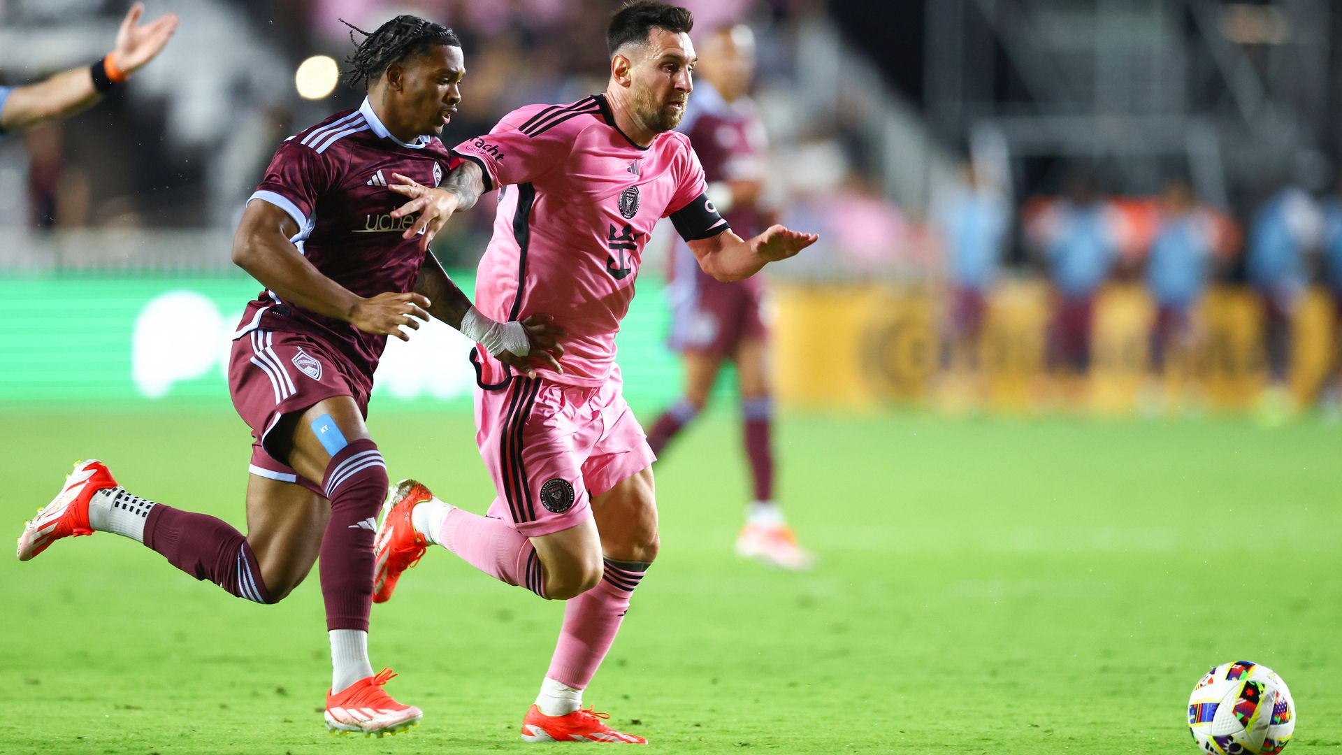 Two men run after the ball during a soccer game. 