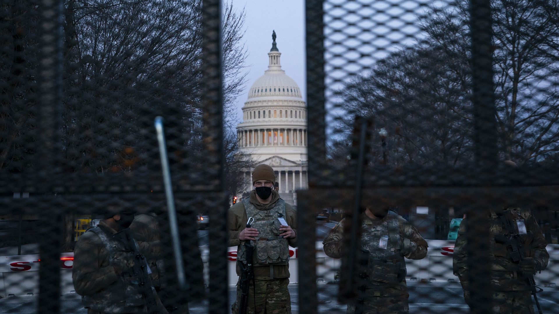 Members of the National Guard stand behind a barbed wire fence permitter surrounding the U.S. Capitol before sunrise on March 4, 2021 in Washington, DC.