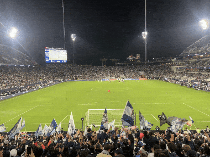 A gif of the crowd waving flags facing the field during a soccer game at Snapdragon Stadium.