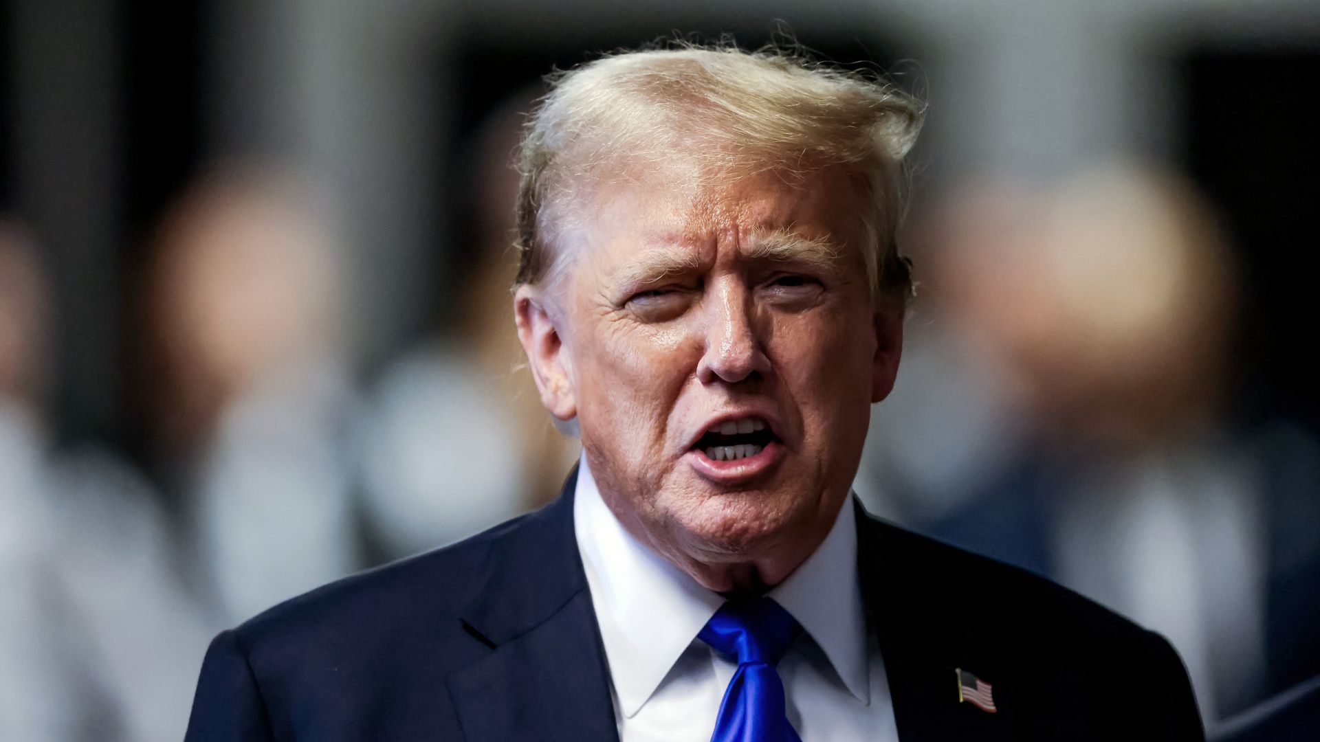 Former President Trump, wearing a blue suit and standing at the Manhattan Criminal Court.