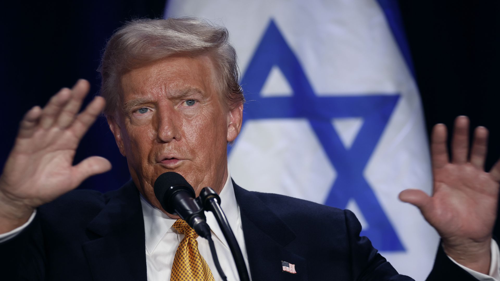 Former President Trump holding up his hands and speaking into a microphone. Former President Trump holding up his hands and speaking into a microphone.