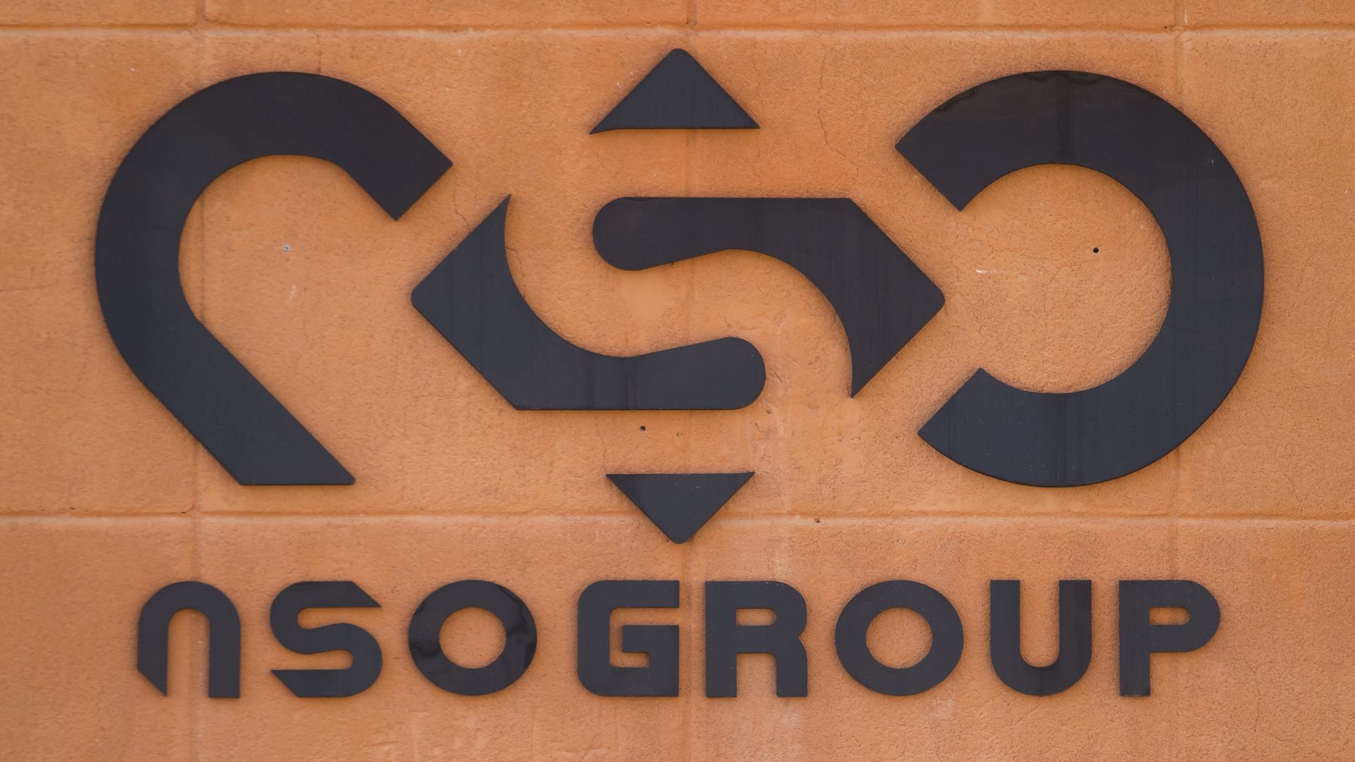 Photo of NSO Group's logo and name printed in black on an orange wall