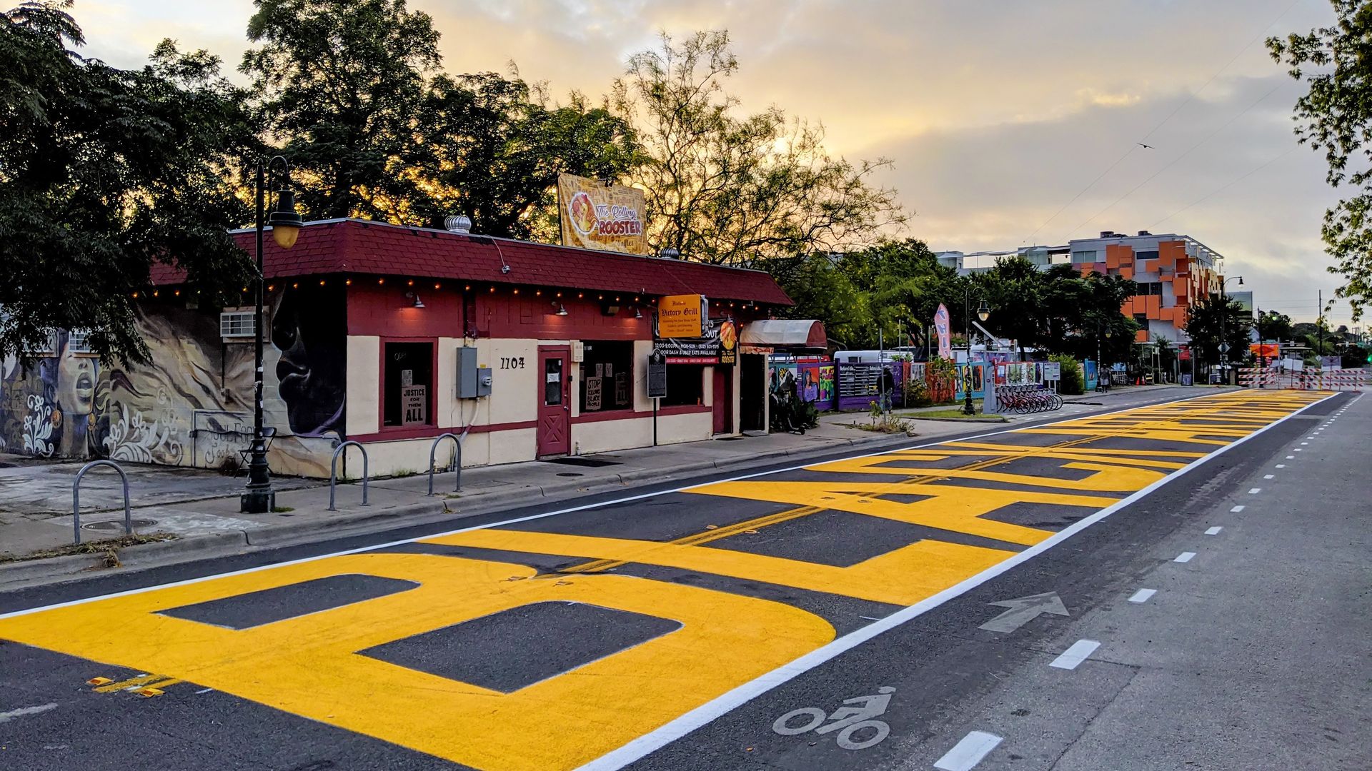 Street view with large yellow "BLACK ARTISTS MATTER" mural painted on the road.