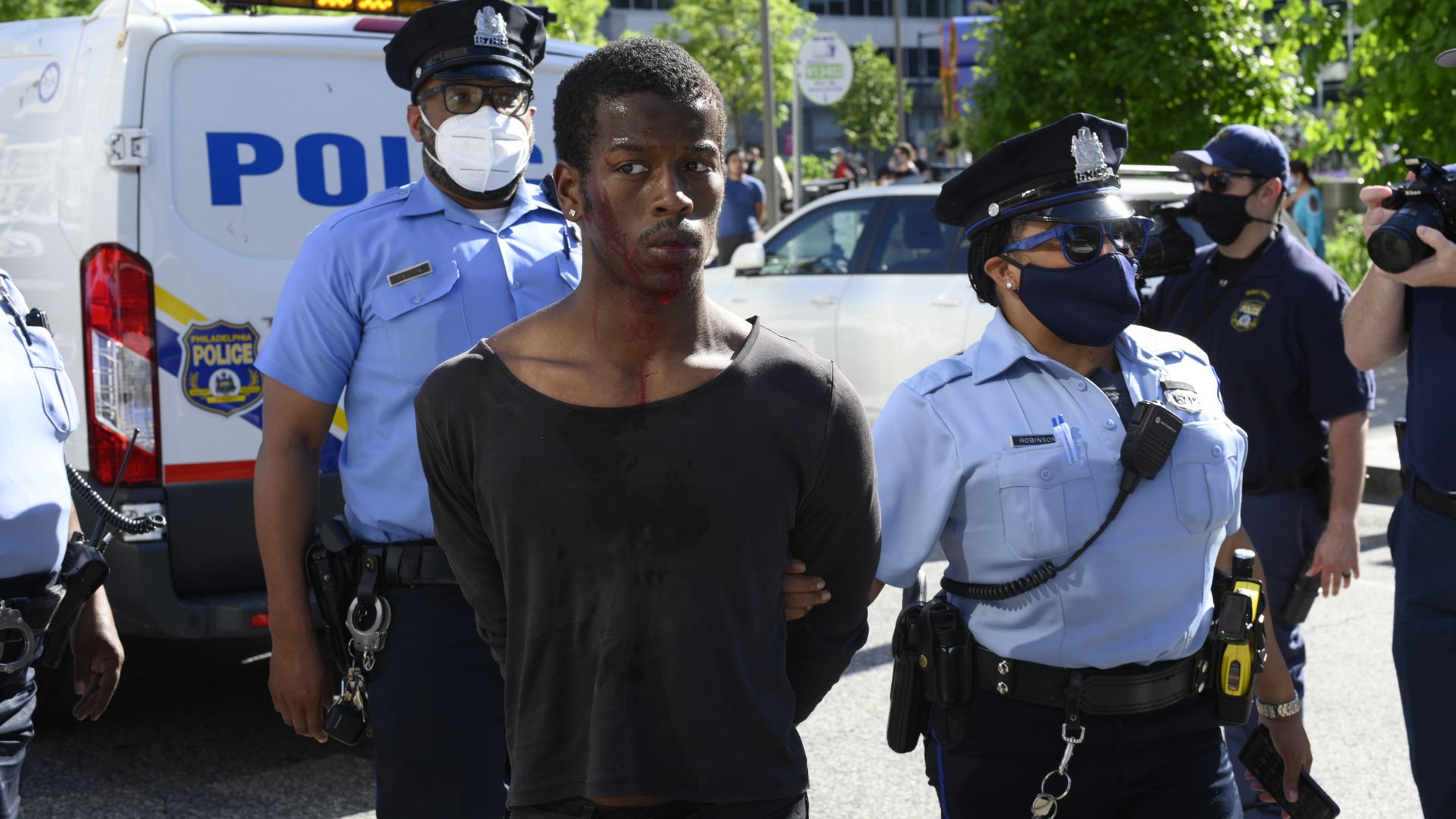 Philadelphia police lead away a young black man under arrest.