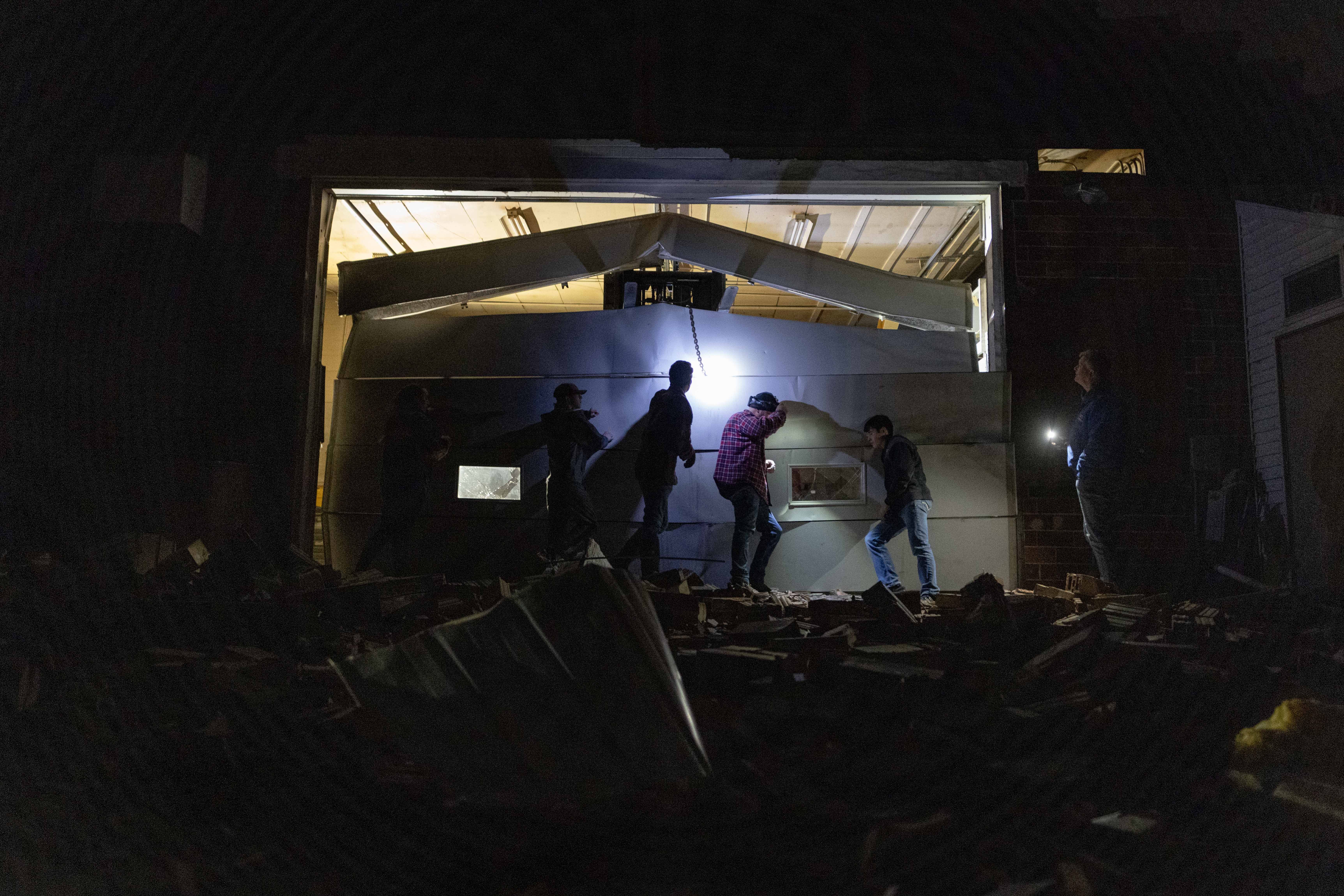 Photo of people holding up a collapsed garage door