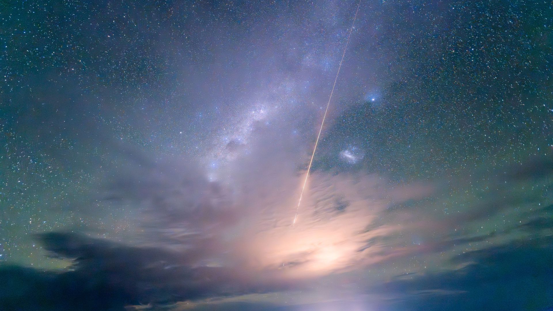 A streak of orange light cuts through a starry night sky. It's an image of an object reentering the Earth's atmosphere at hypersonic speeds.