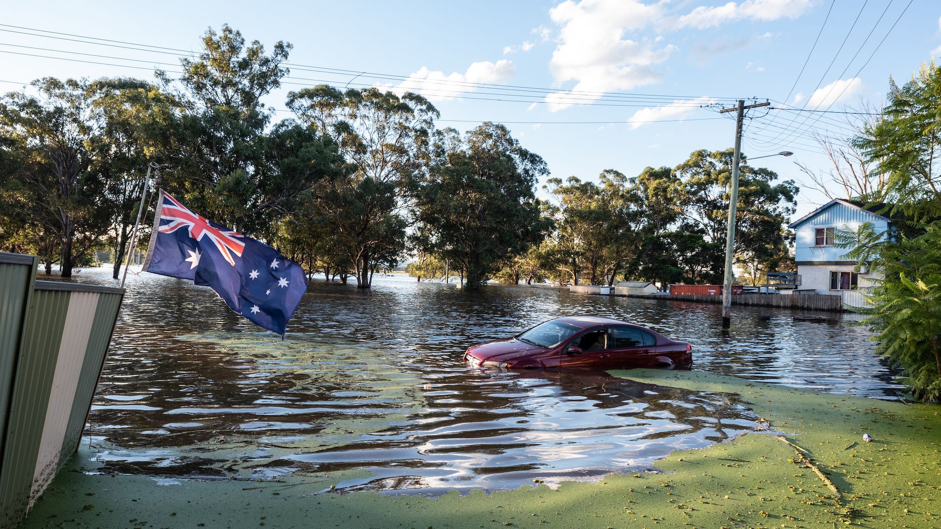 A photo of A car submerged in water with the australian flag in the foreground.