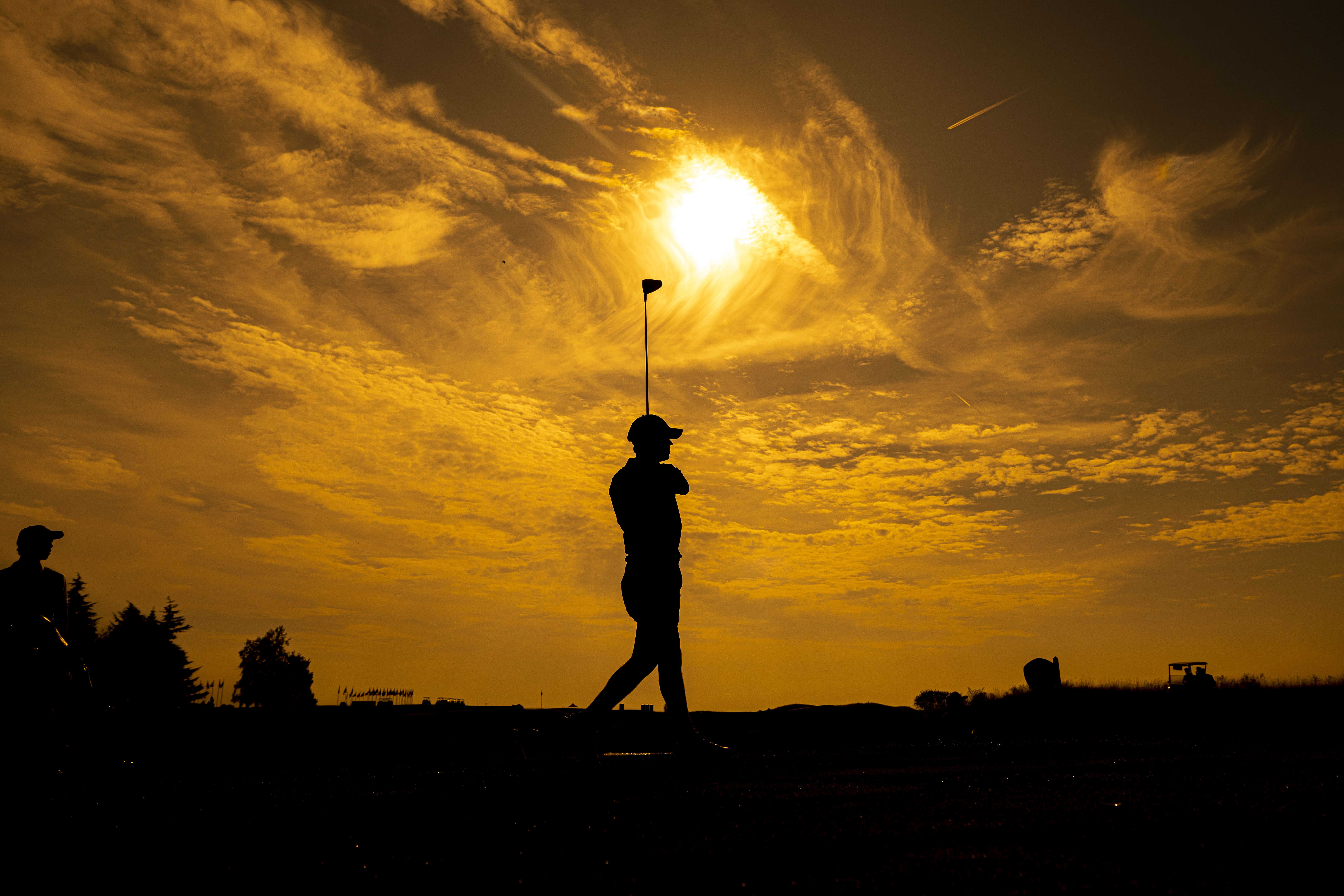 golfer swinging in sunset