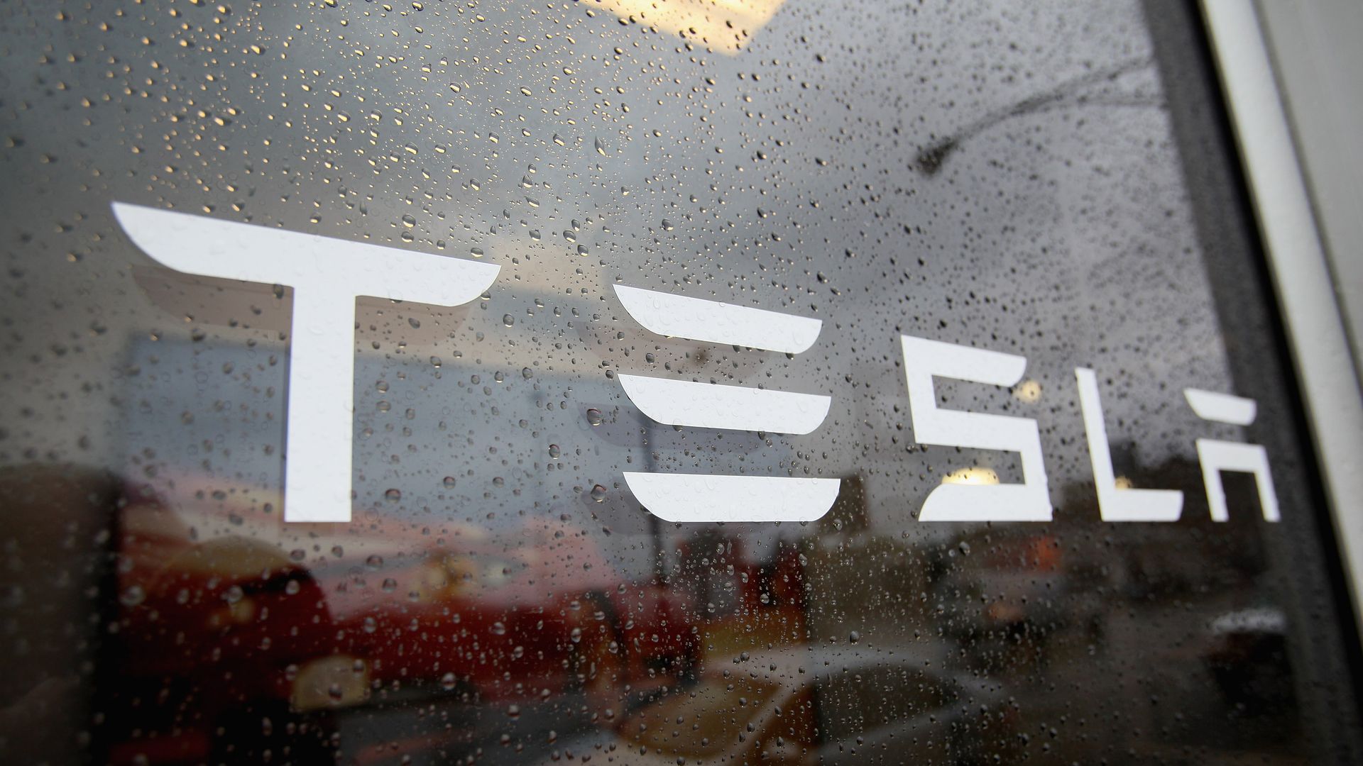 The Tesla logo on a window with rain.