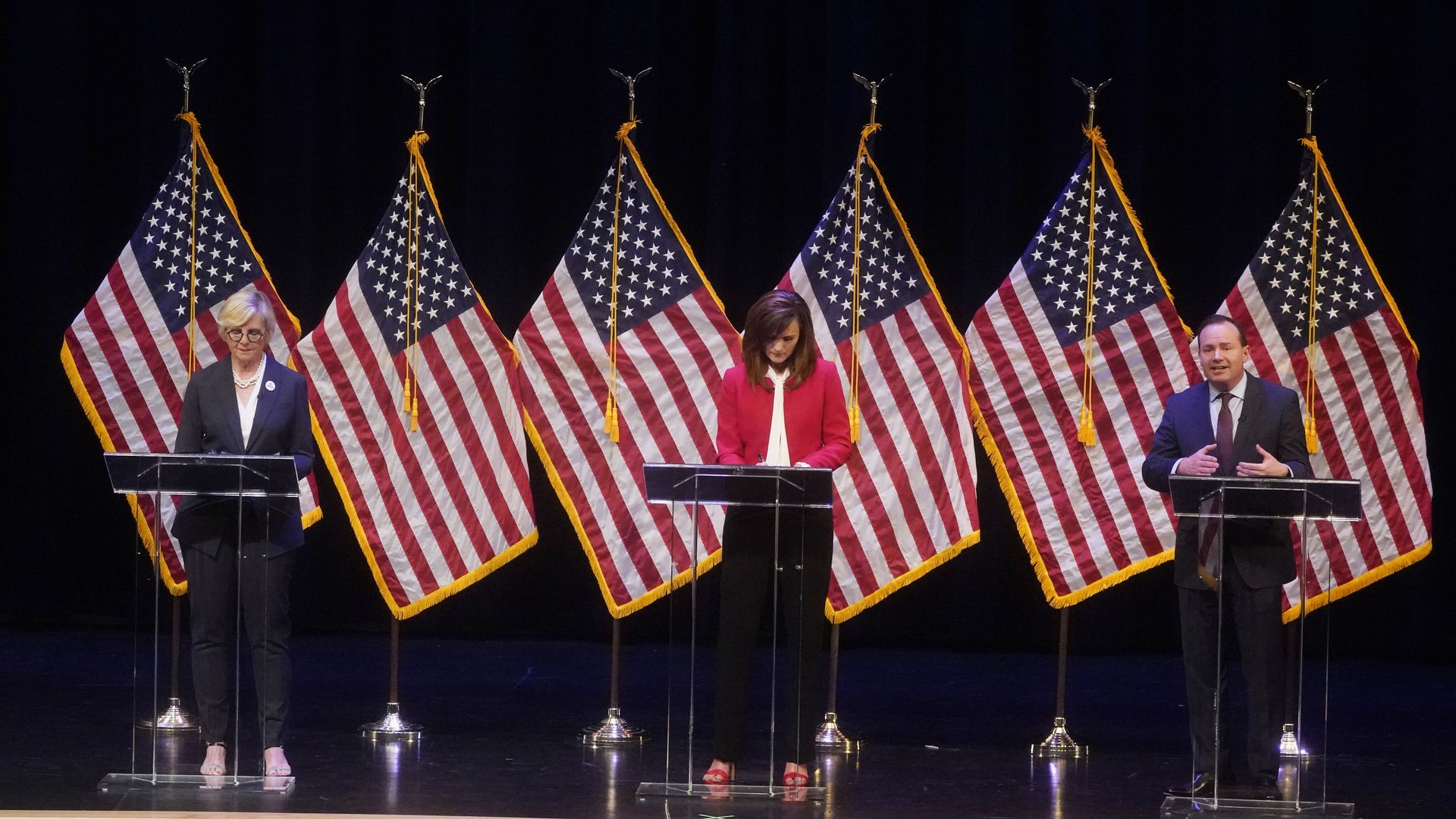 Three people debating behind podium.