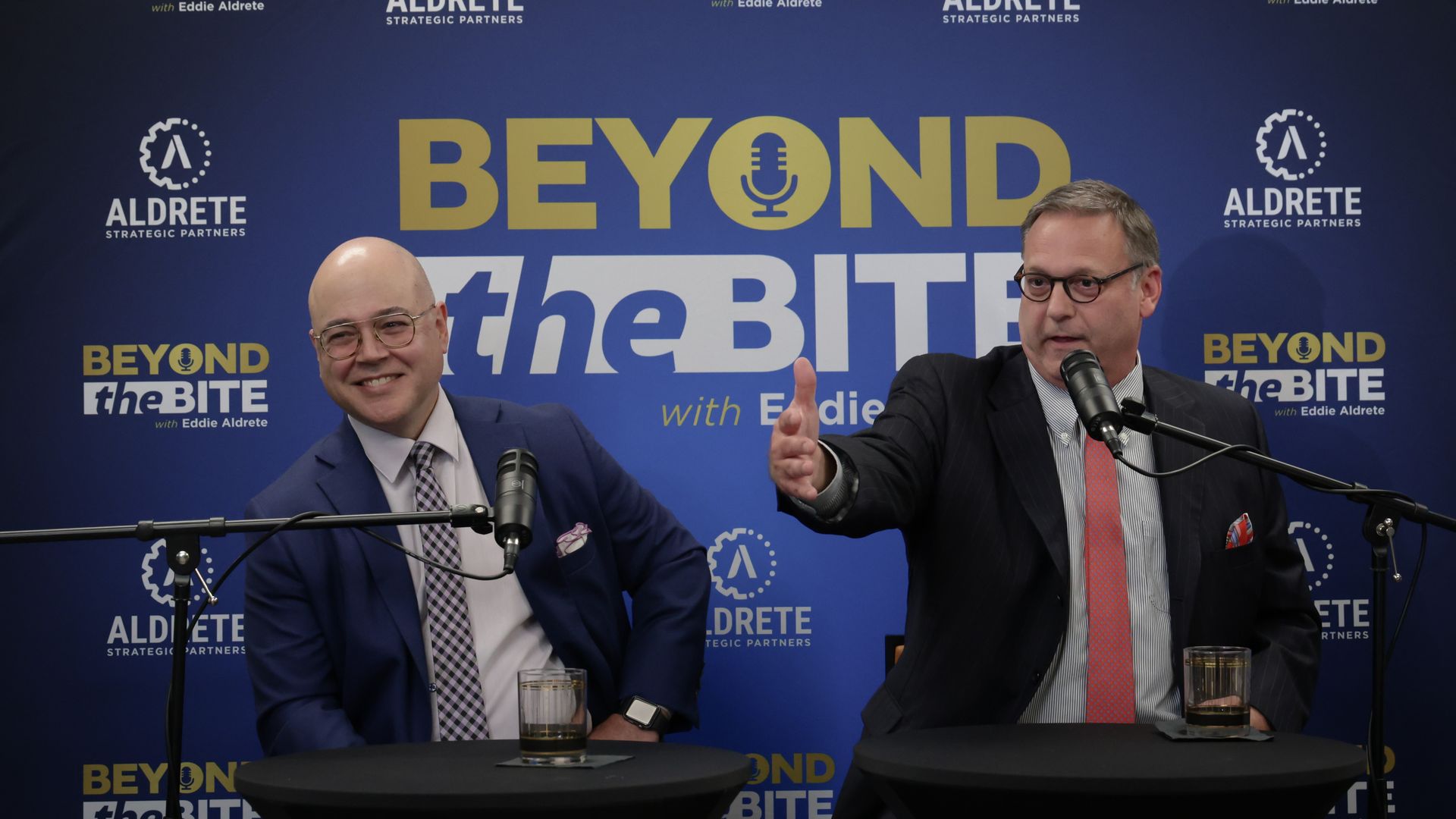 James Aldrete and Kelton Morgan at a live recording of the "Beyond the Bite" podcast, sitting in front of microphones.