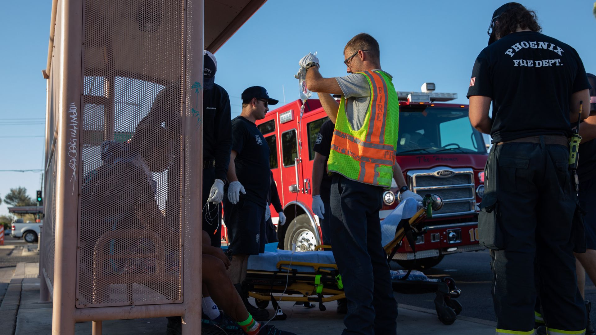 Firefighters assisting a man at a bus stop. 