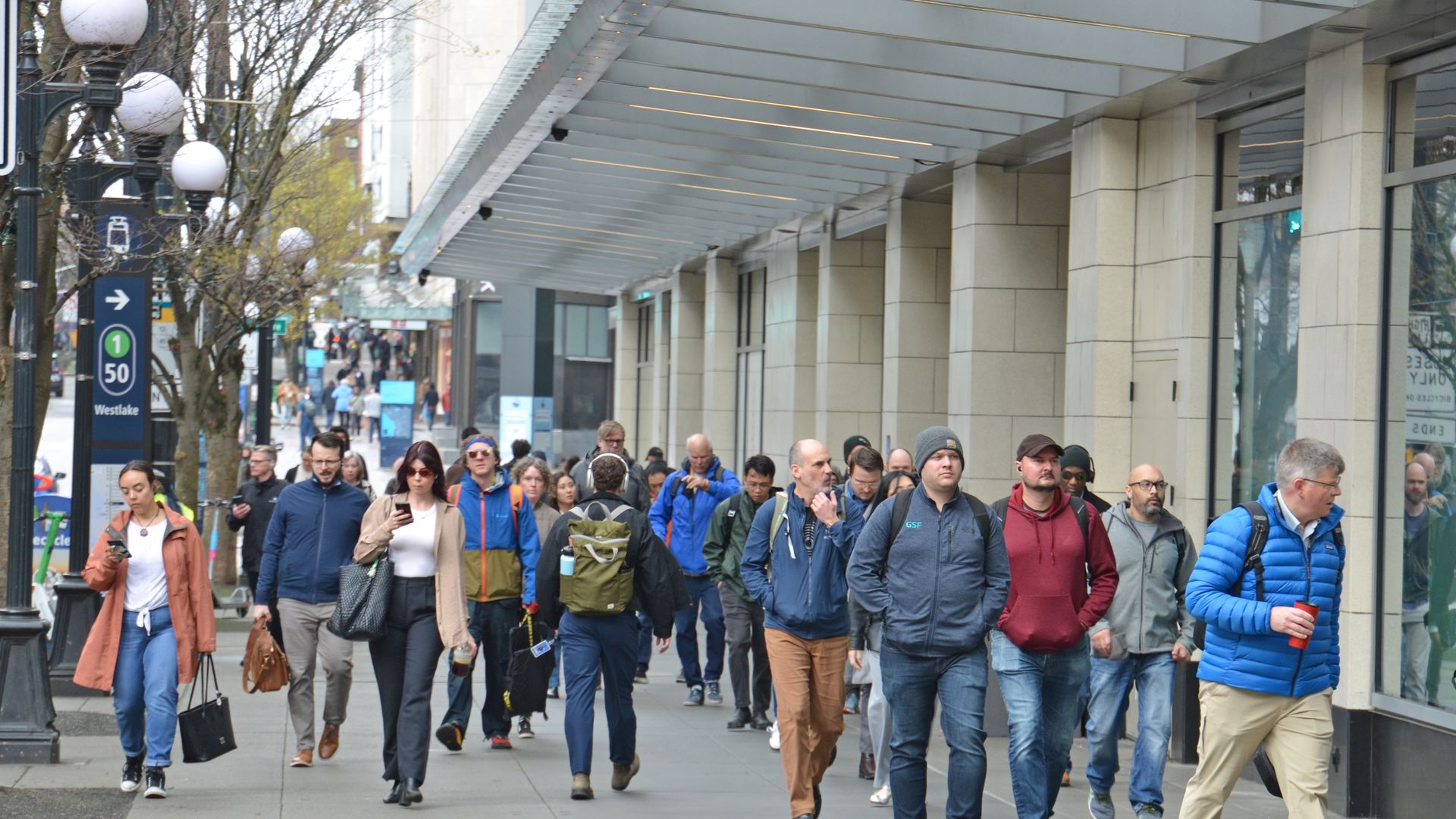 A crowd of pedestrians walk along a street in downtown Seattle. 