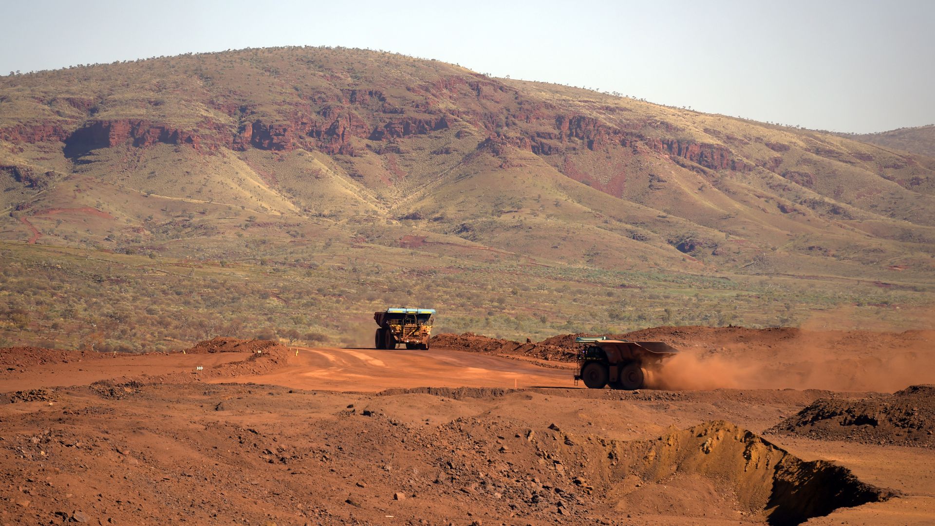 Trucks travel along an access road at the Gudai-Darri iron ore mine operated by the Rio Tinto Group in the Pilbara region of Western Australia, Australia, on Tuesday, June 21, 2022. 