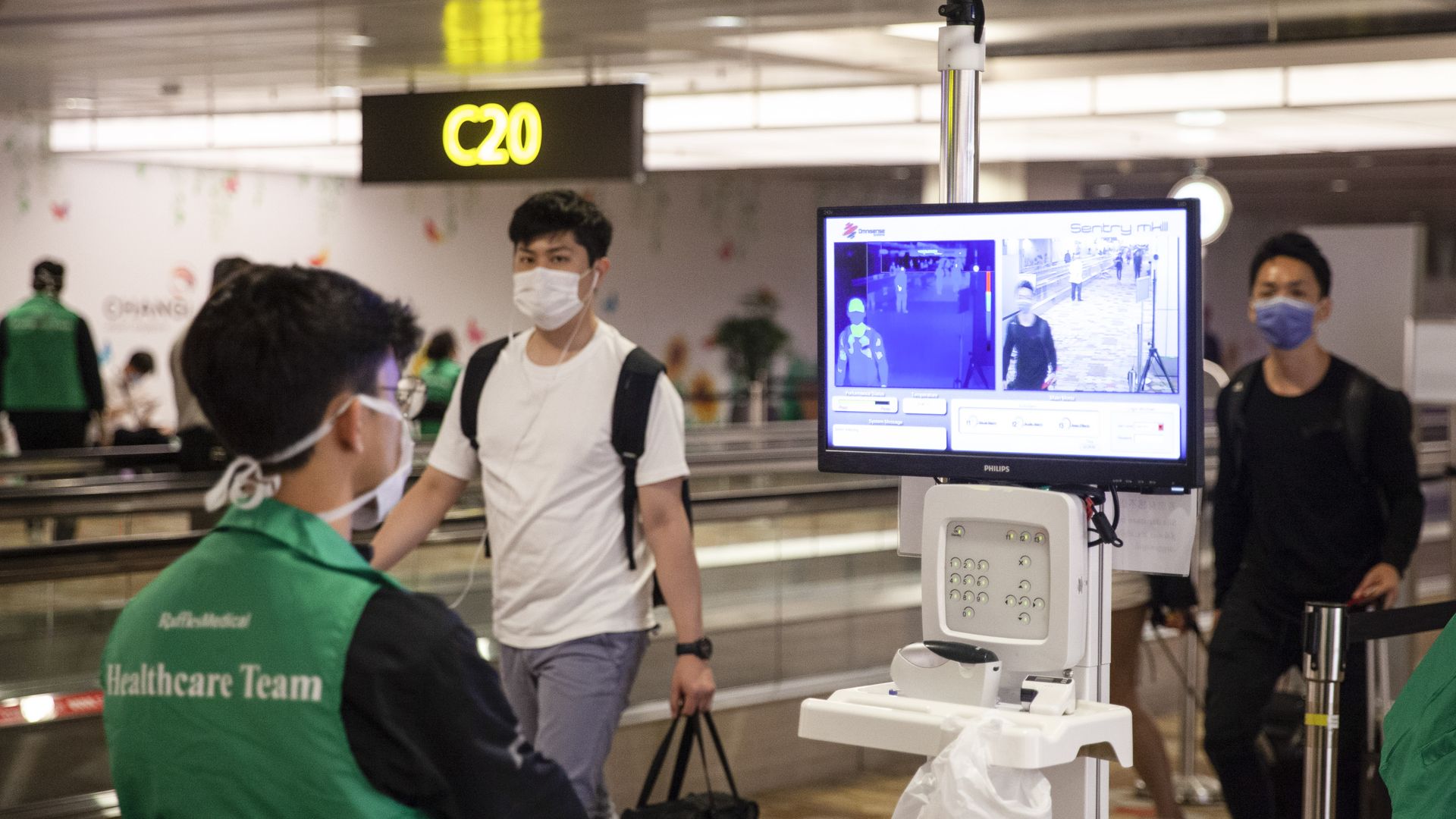 Members of a healthcare team monitor temperature screening equipment as travelers pass thermal monitors at Changi Airport in Singapore, on Wednesday, March 11, 2020.