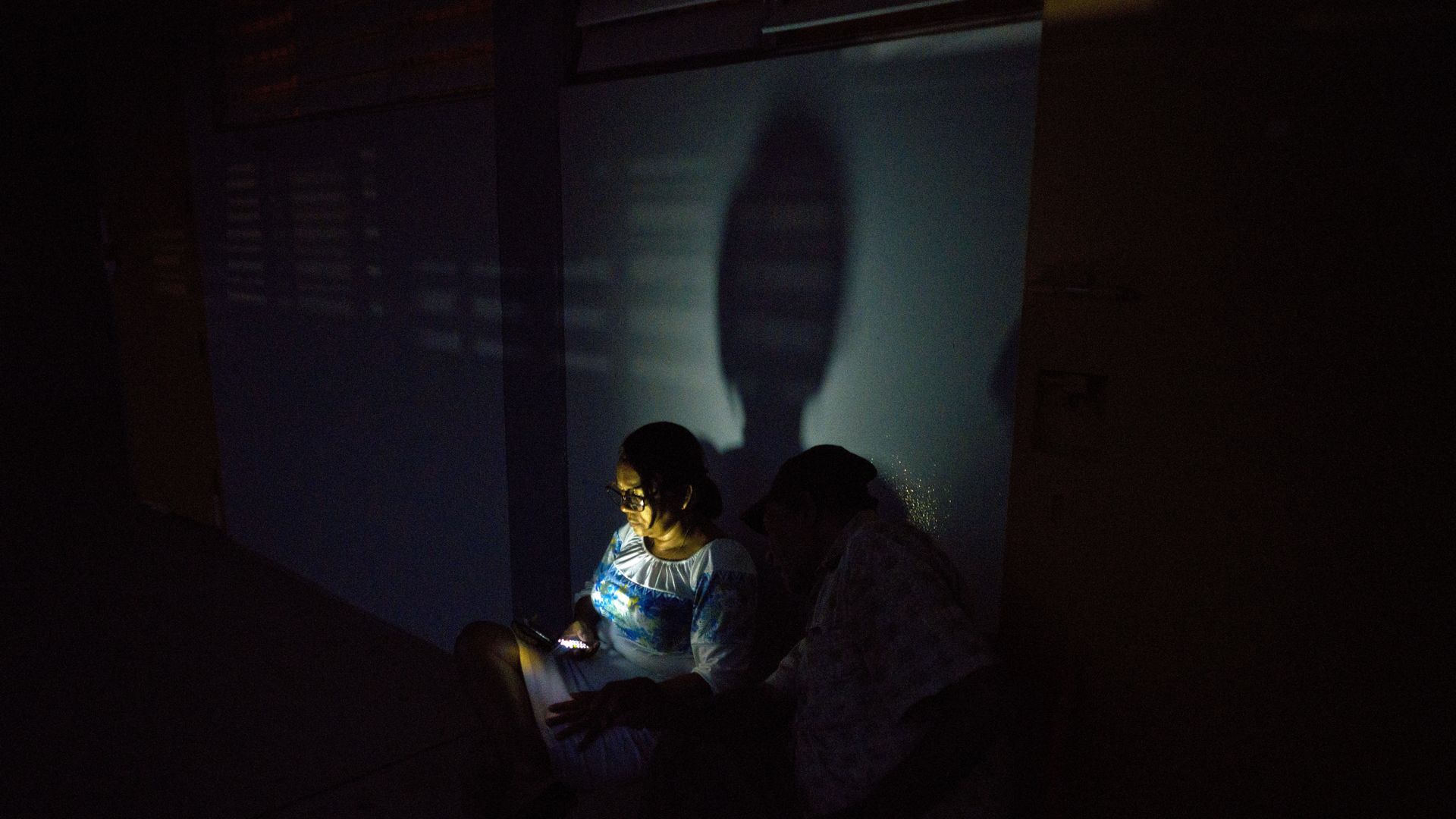 A woman left homeless by Hurricane Maria uses her cell phone at a school-turned-shelter that does not have electricity in Toa Baja, Puerto Rico.