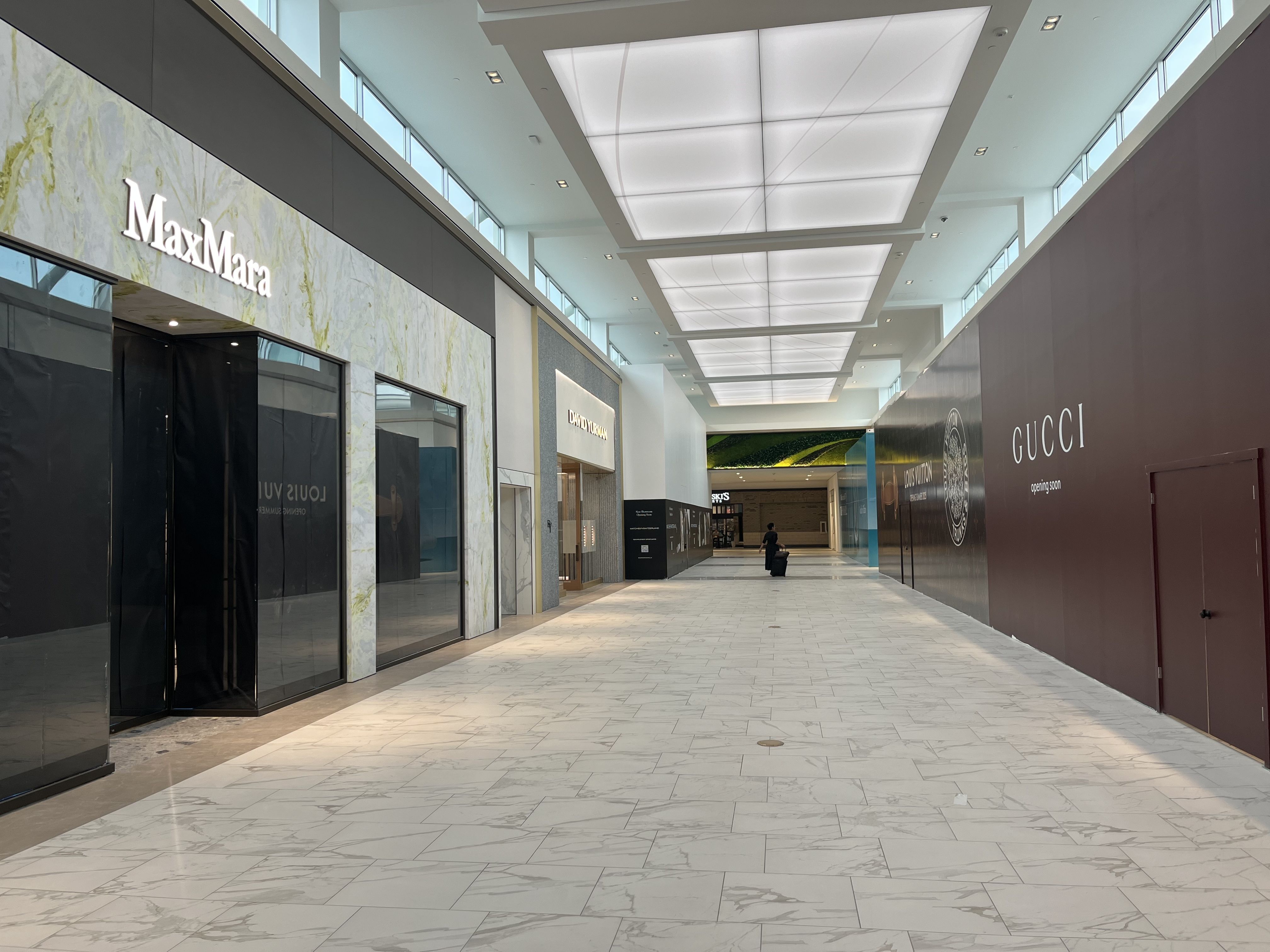 An empty hallway with luxury retailer branding showing the stores under construction 