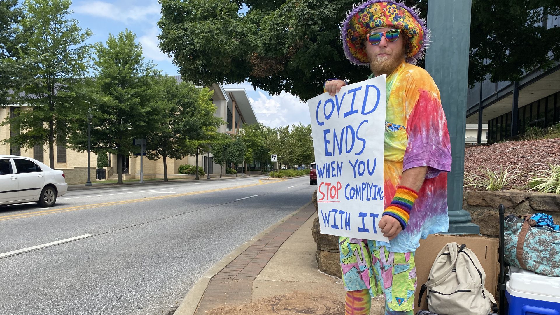 A man wearing rainbow-colored clothes protests against vaccines. 