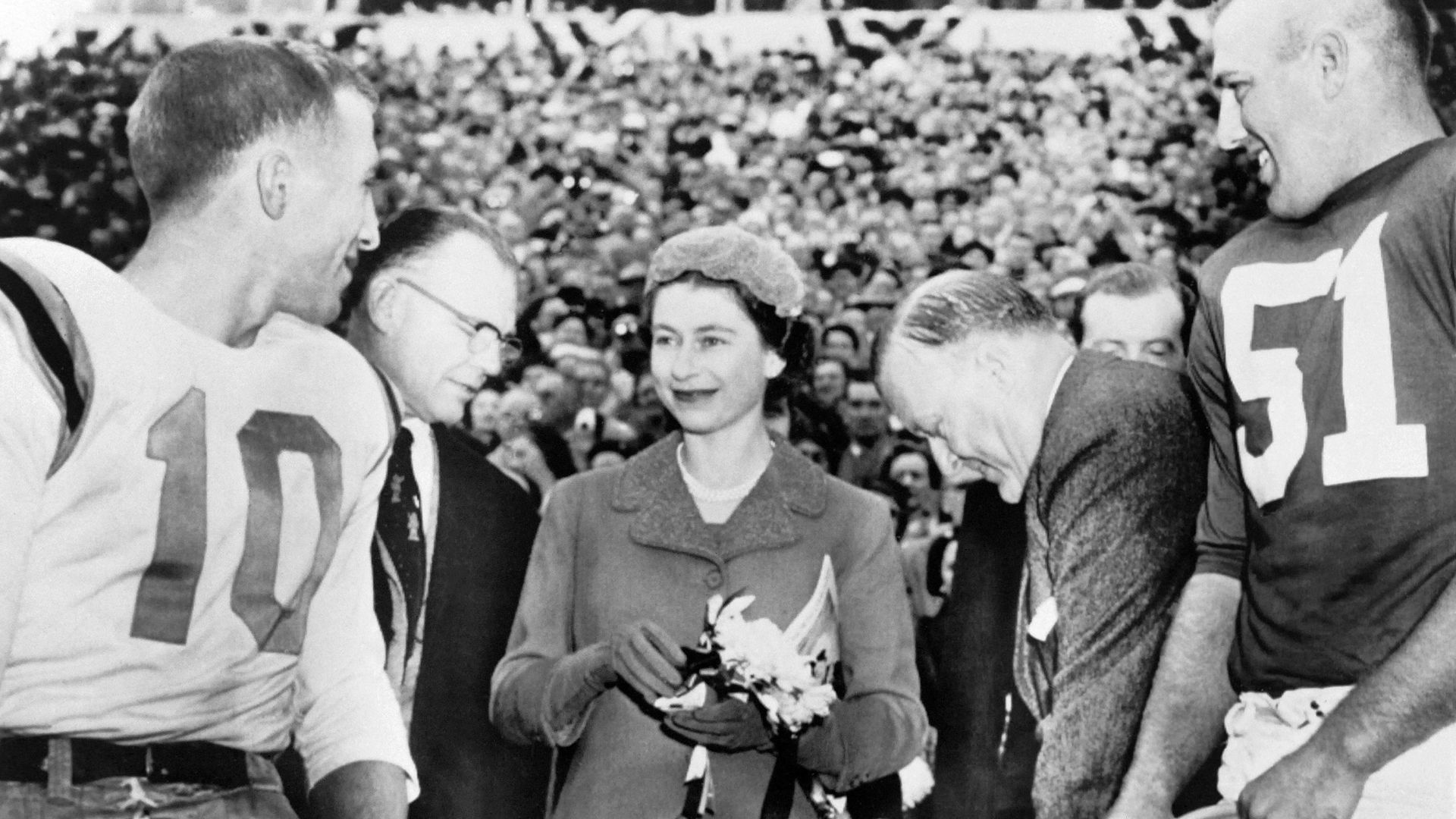 A black and white photo of Queen Elizabeth II with football players from North Carolina and Maryland.