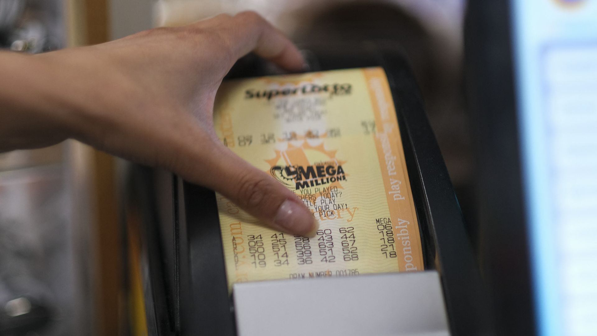 Hand taking Mega Millions lottery ticket out of printer