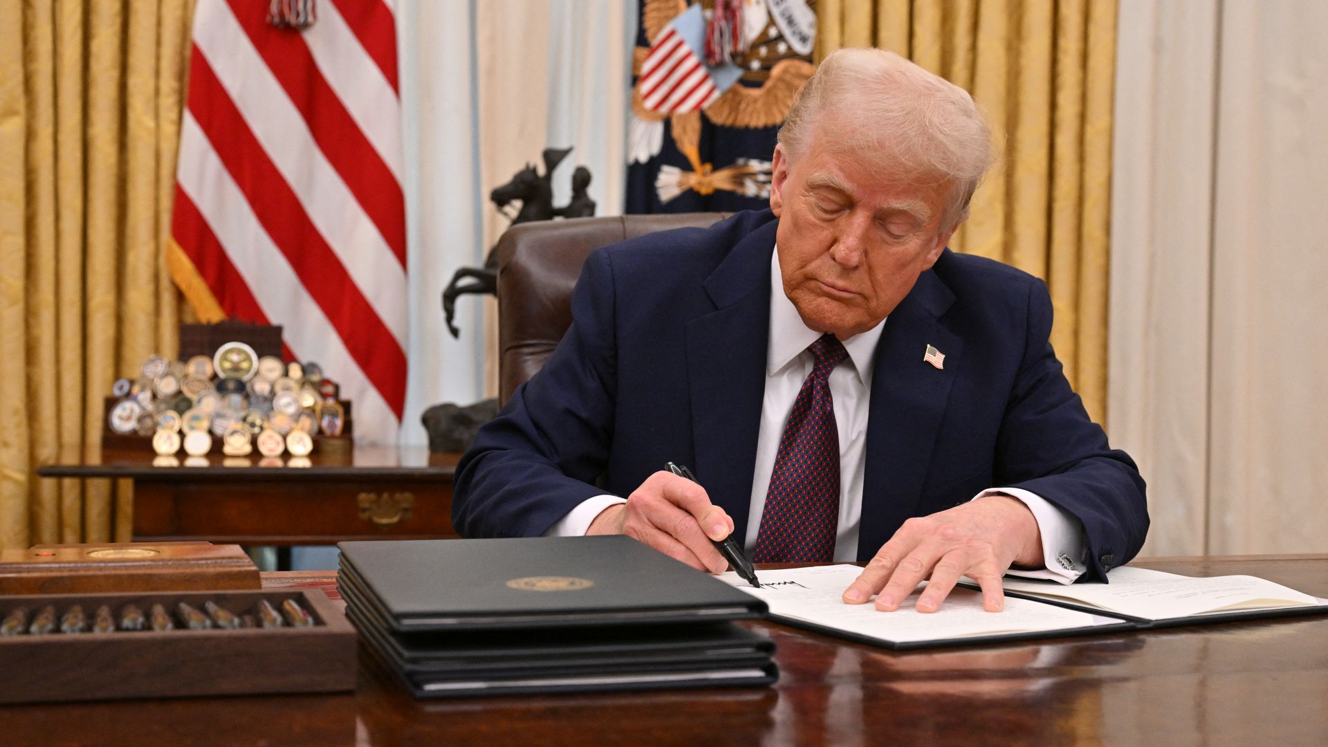 President Trump signing documents in the Oval Office. 