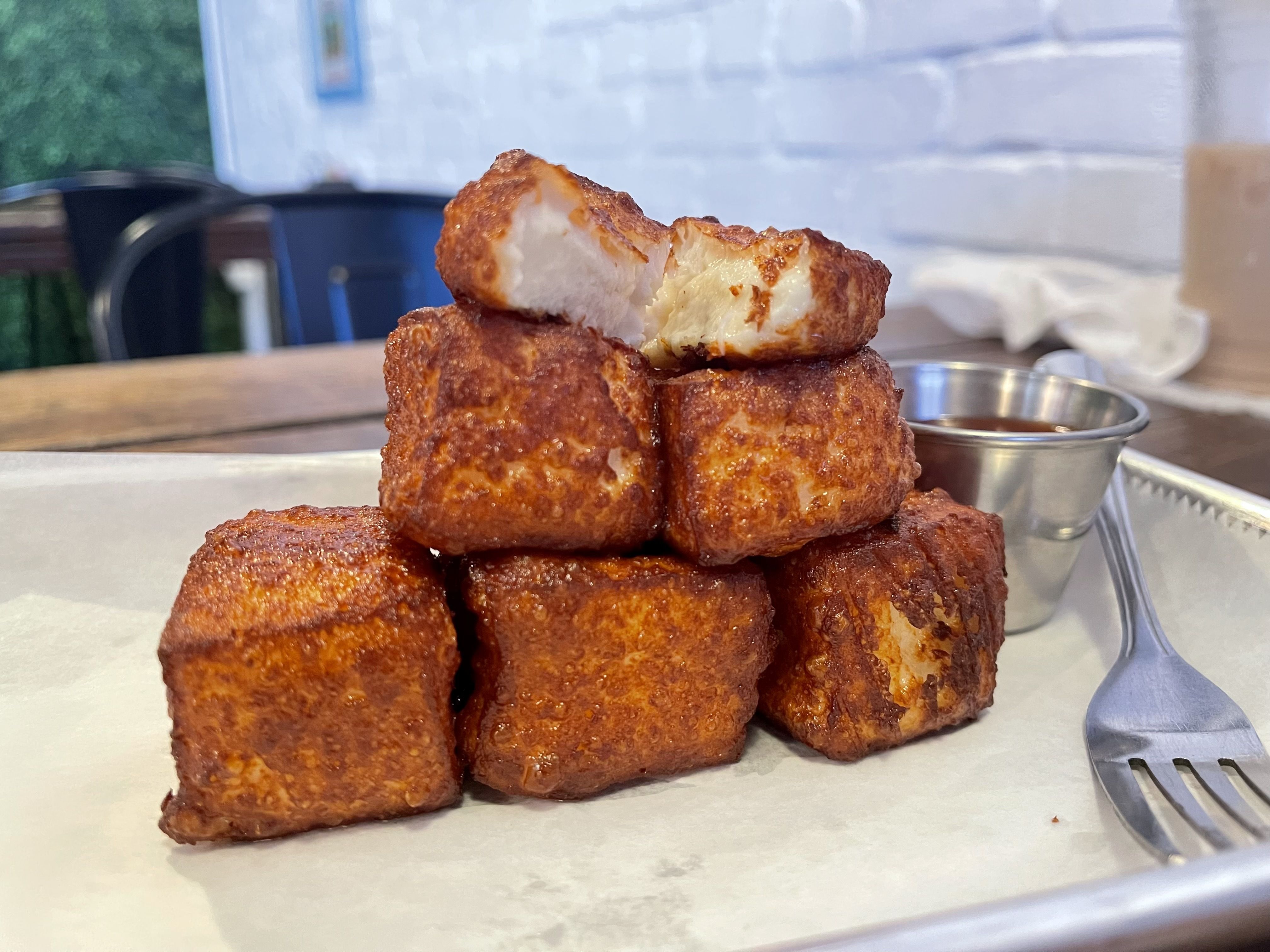 A pyramid of fried cheese cubes with a cut up one on top