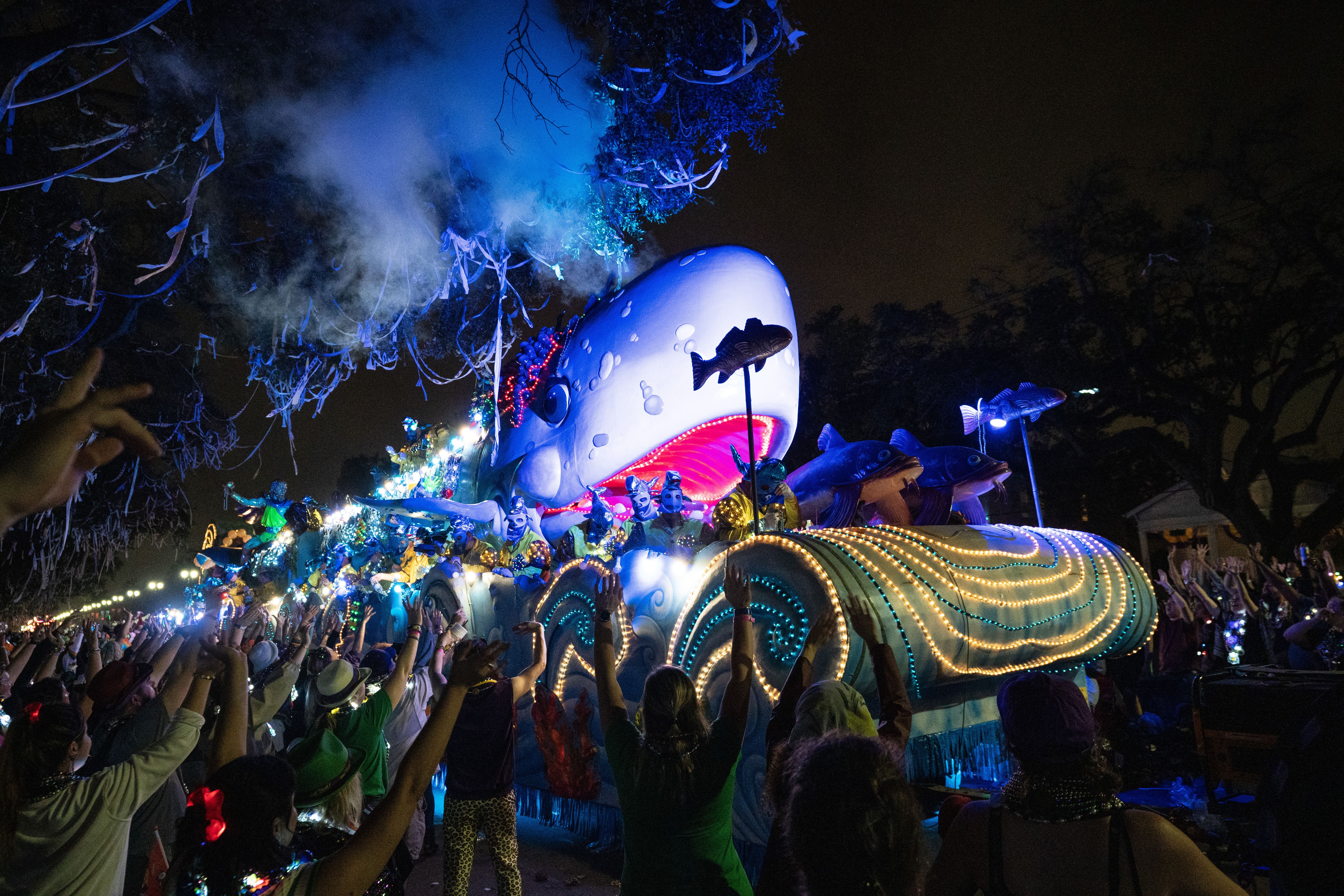 A whale-shaped float heads down the parade route, lighted up at night.