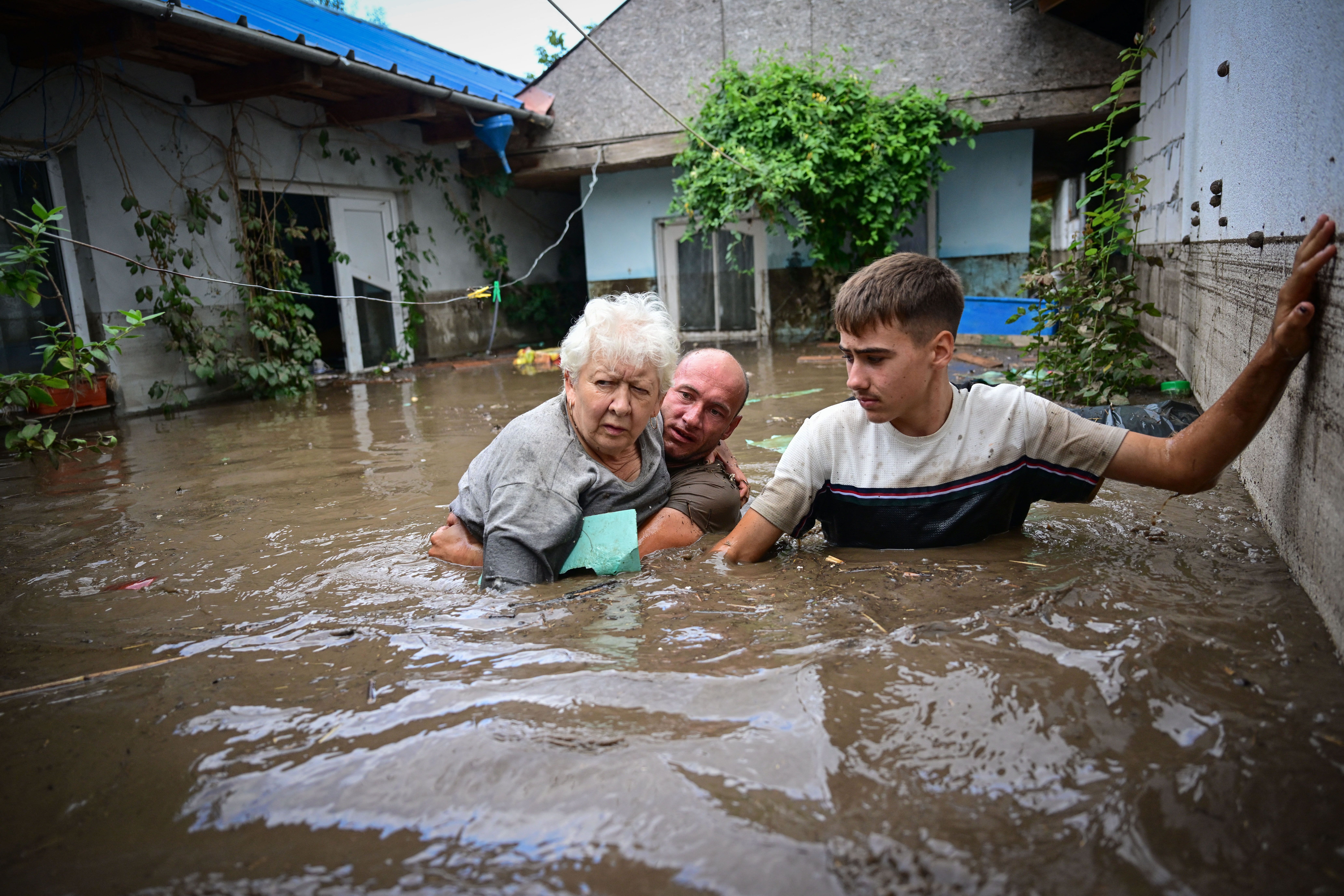 Local residents rescue an elderly man (C) from the rising flood waters in the Romanian village of Slobozia Conachi on September 14 