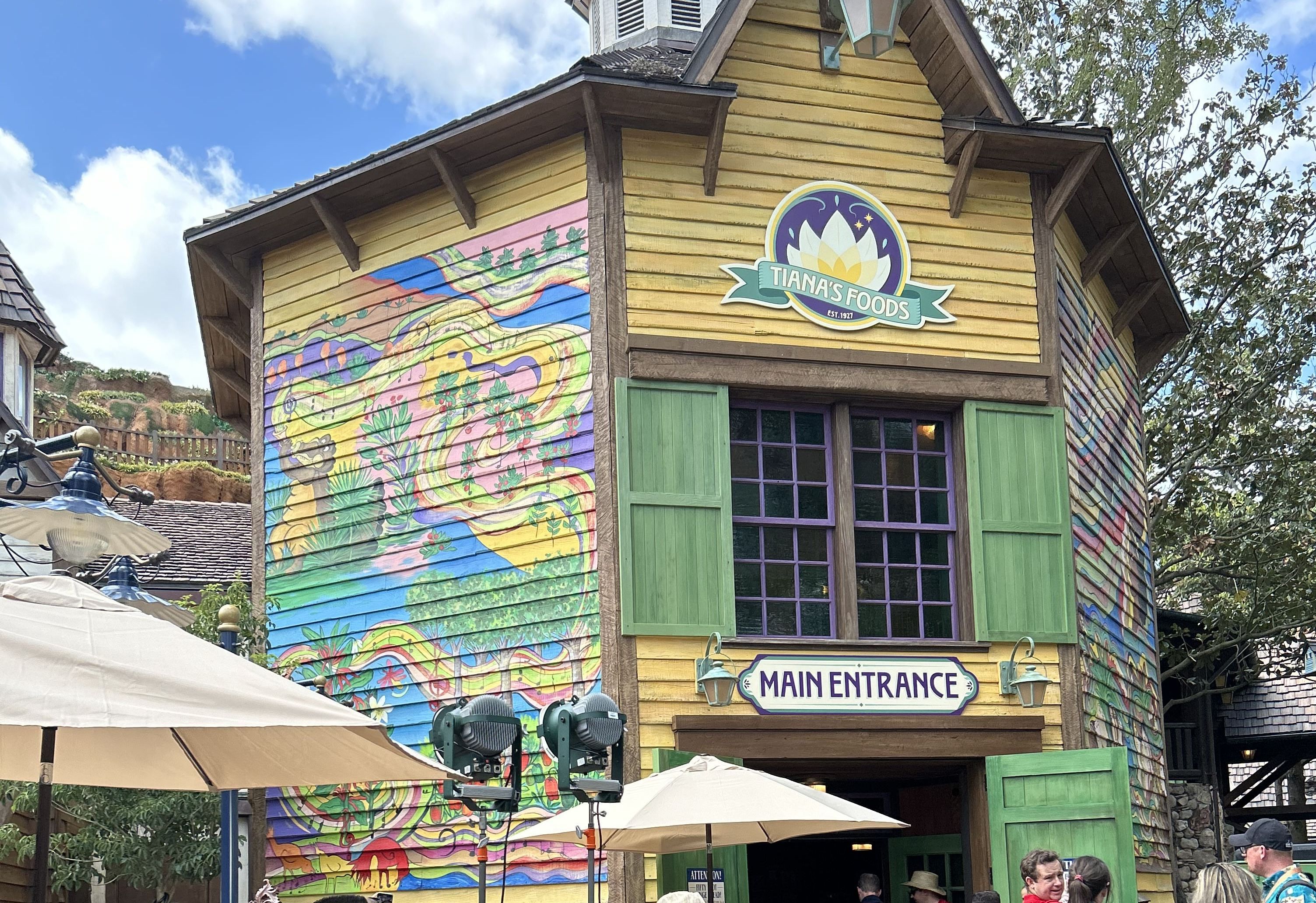 Photo shows the entrance of Tiana's Bayou Adventure with a colorful mural on the side of the building.