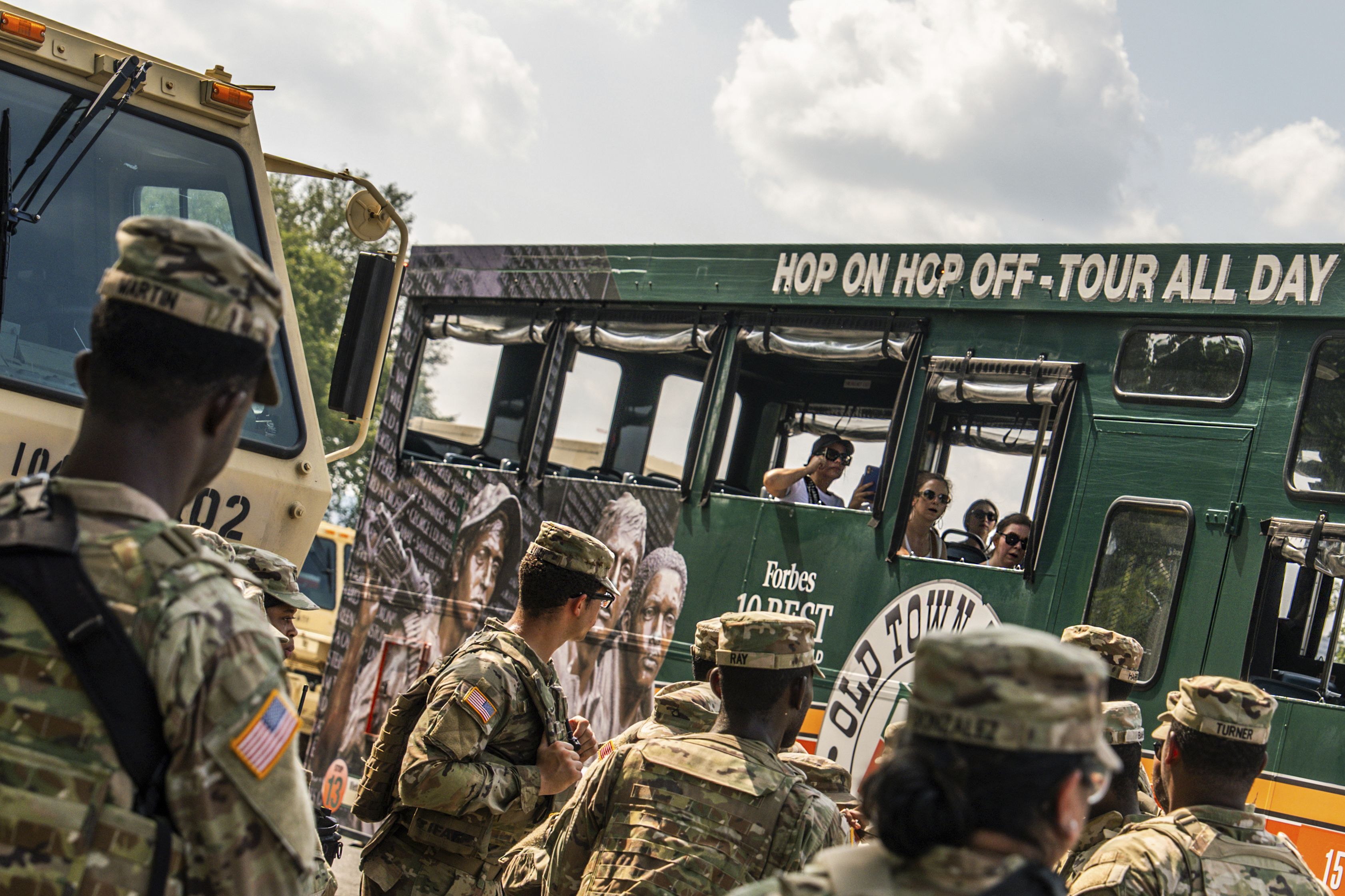 A tour bus passes members of the D.C. National Guard yesterday.