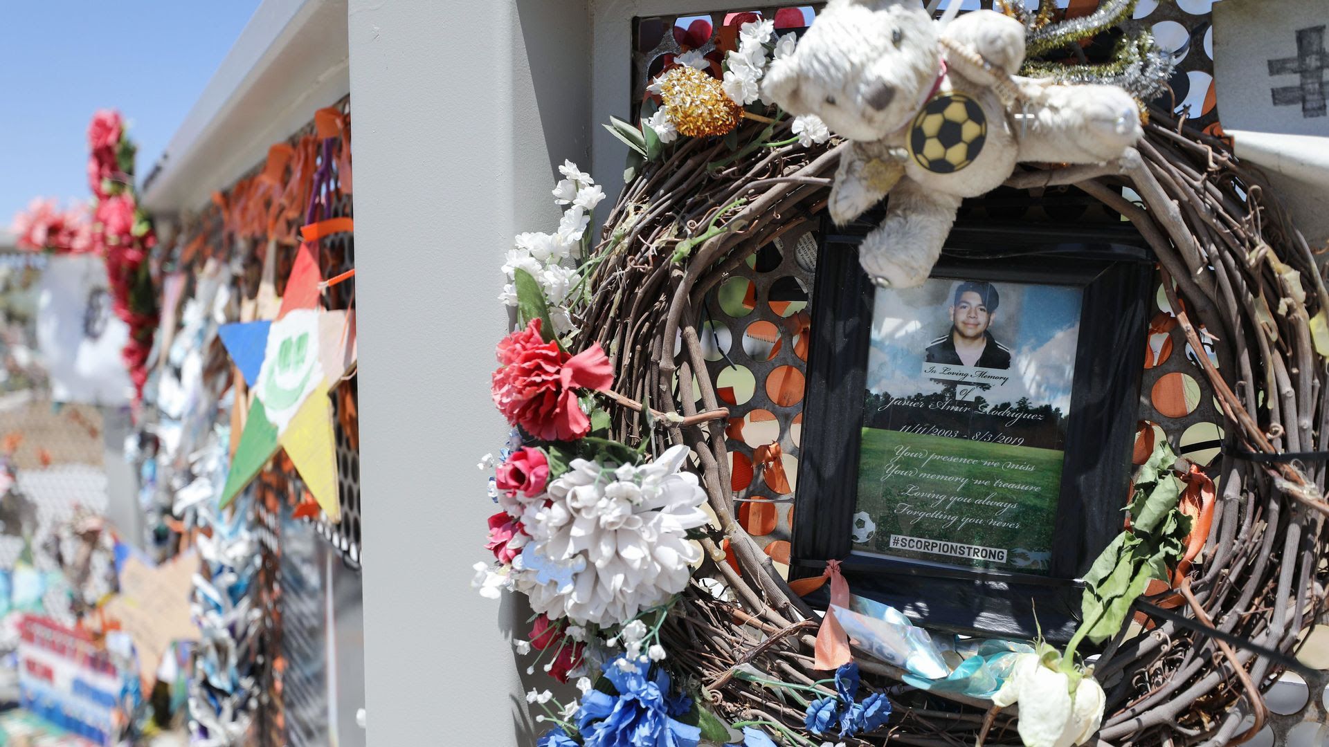 A wreath with flowers hangs at a memorial site. 