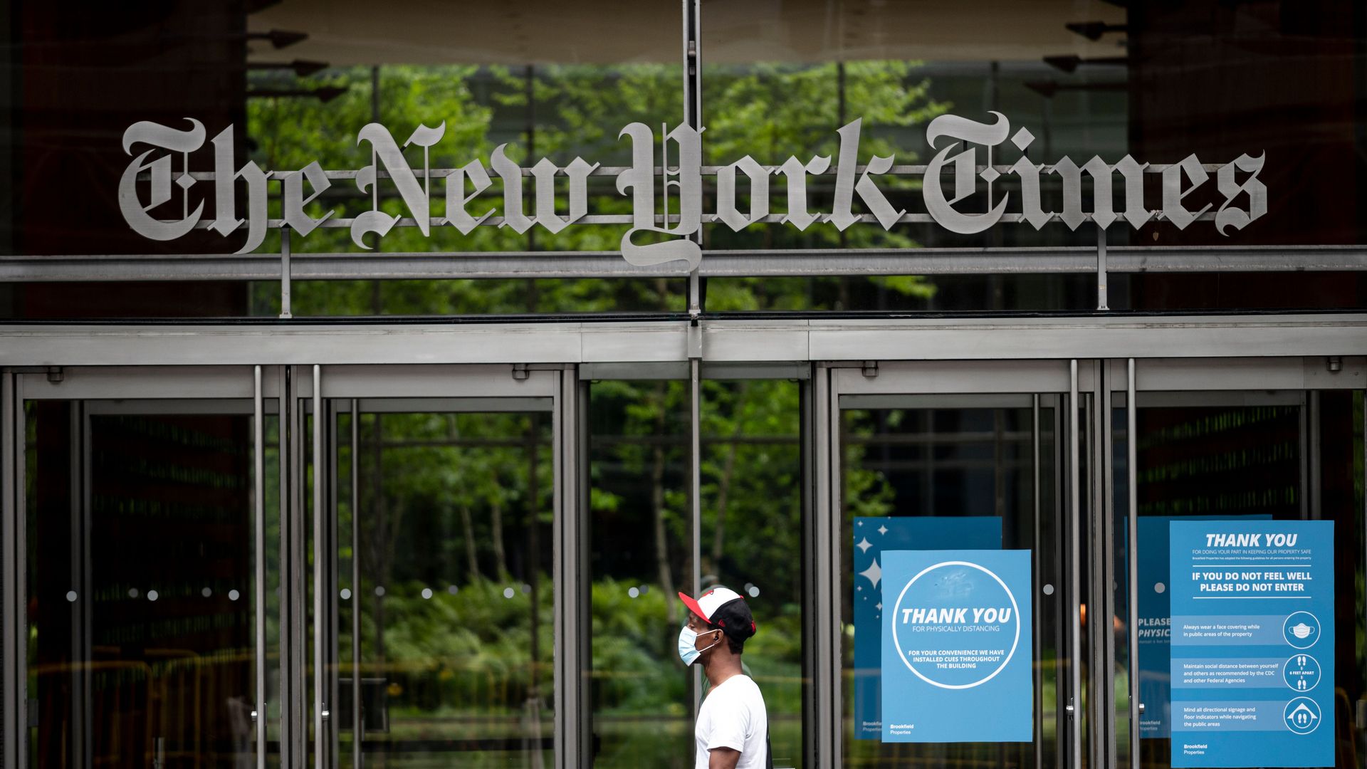 Photo of a person walking in front of the entrance to the New York Times building