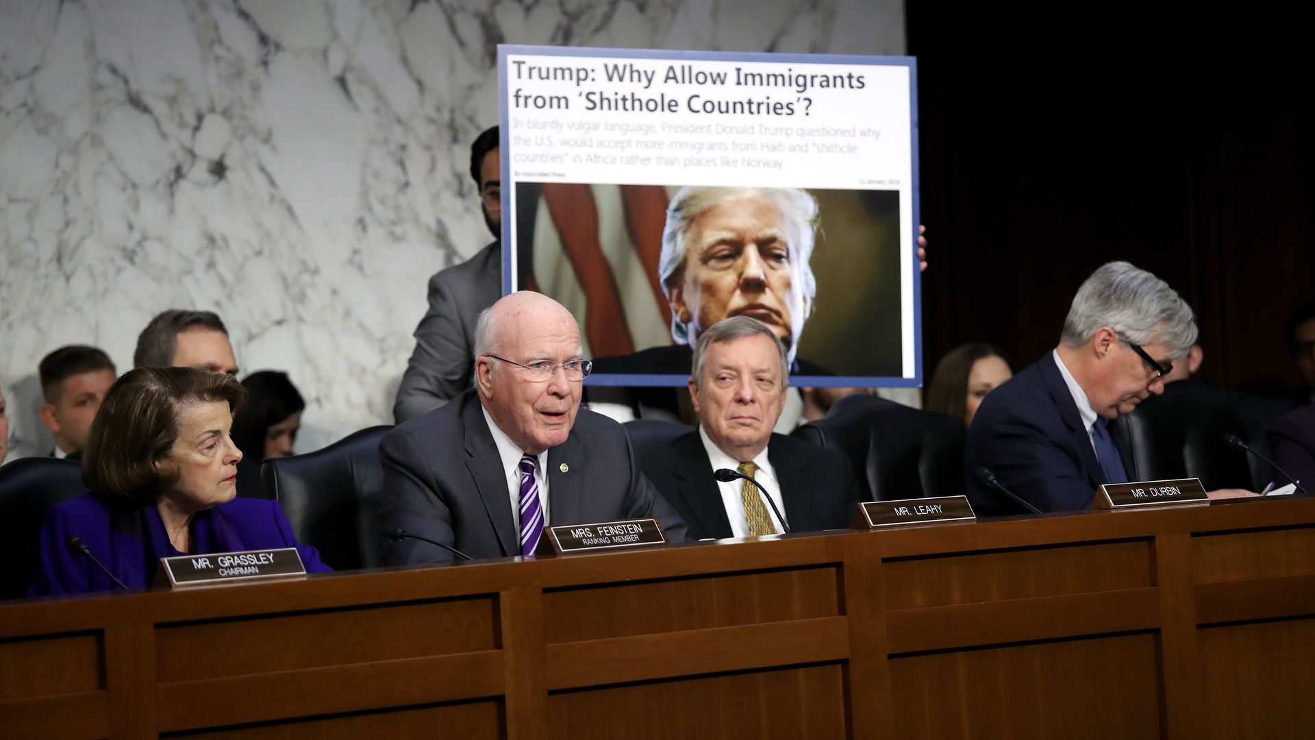 The Senate Judiciary Committee confers with an aide holding up a screenshot of a headline with Trump's vulgar language