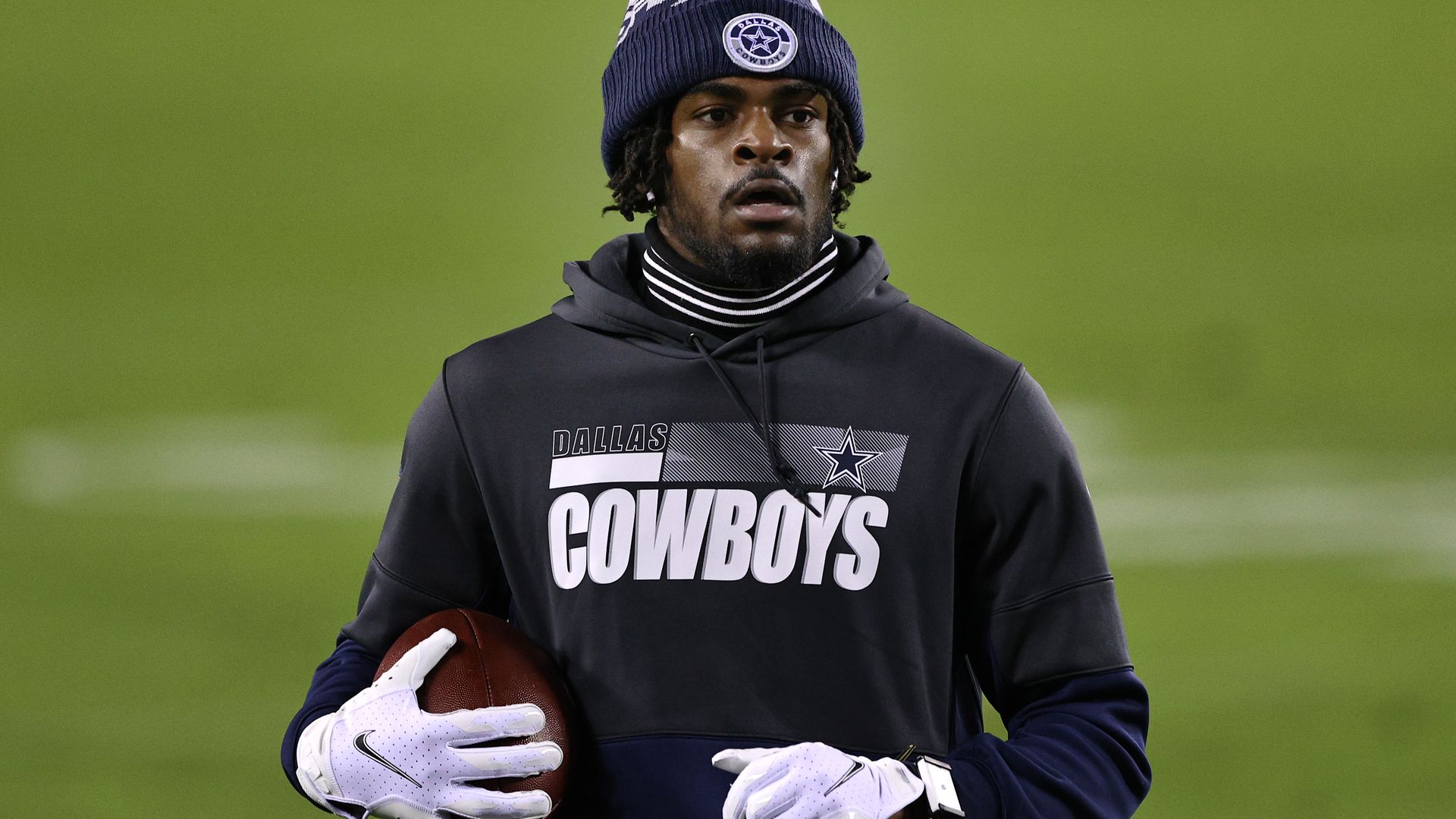 Trevon Diggs in a sweatshirt, holding a football