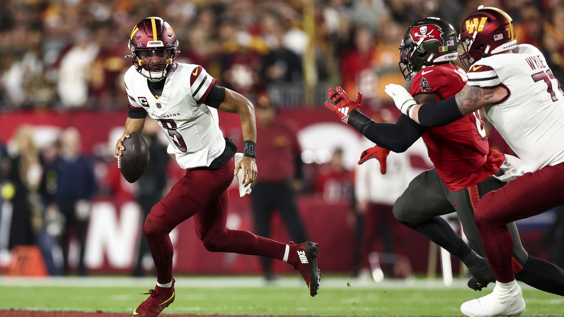Commanders QB Jayden Daniels carries the ball. 