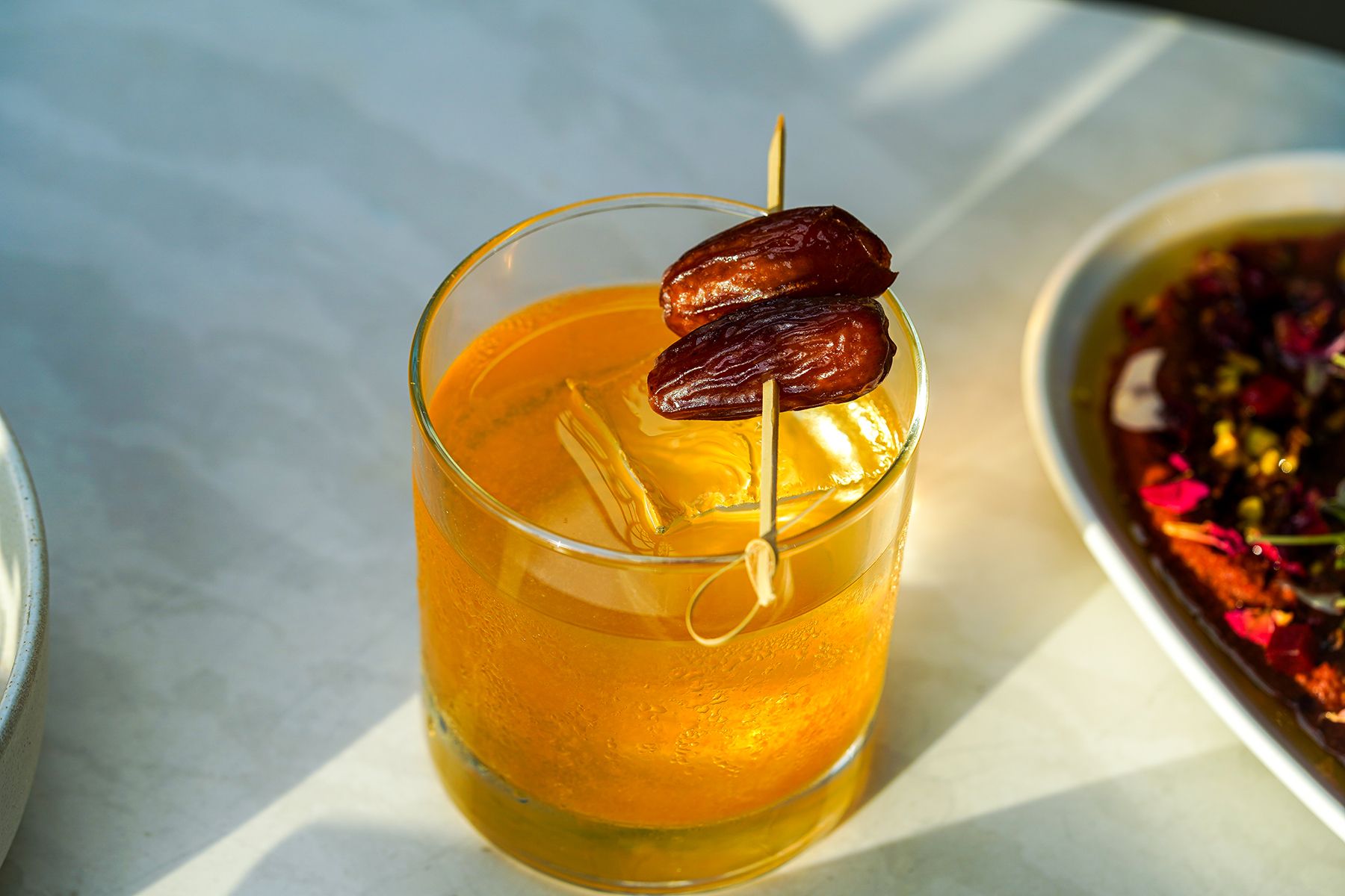 An orange cocktail garnished with dates
