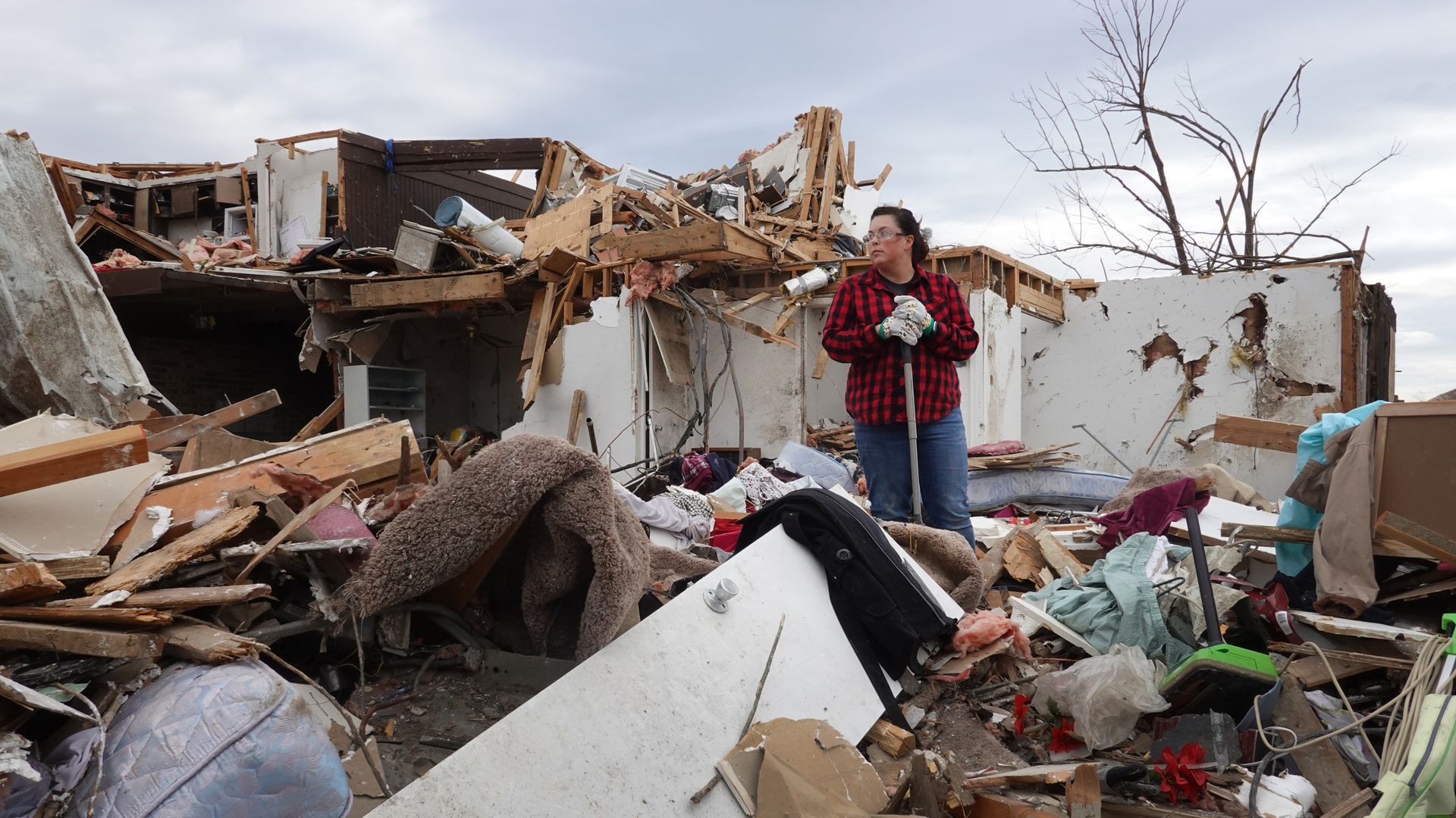 Picture of a woman standing among wreckage from the Kentucky tornadoes