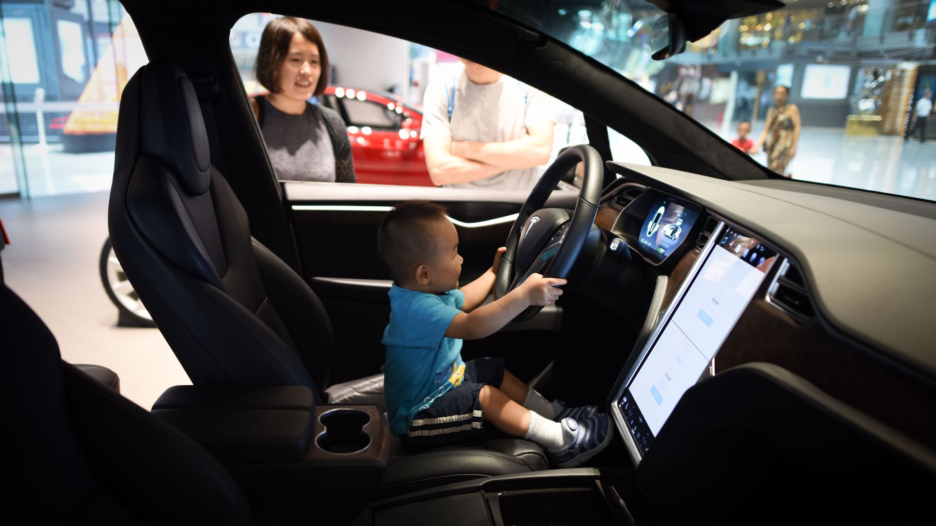 Baby in the front seat of a showroom tesla car