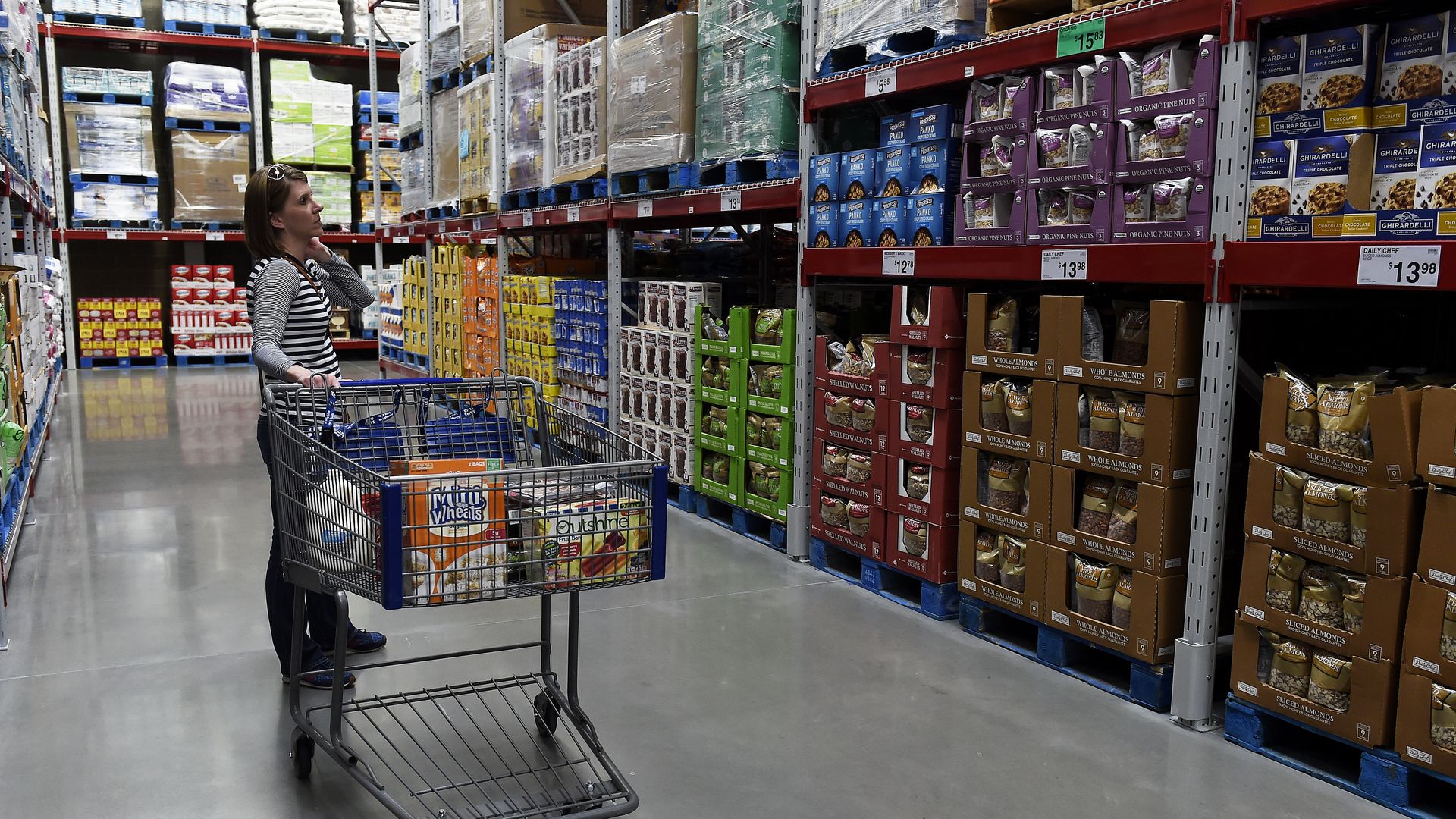 A woman browses a Sam's Club aisle stocked with products in bulk