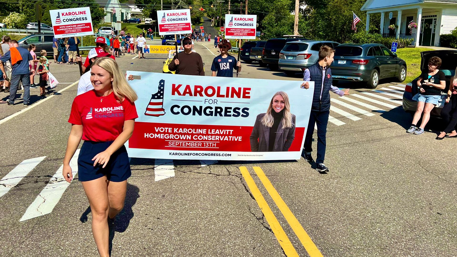 Karoline Leavitt, a candidate for U.S. House in New Hampshire's 01 district, walks in front of a campaign banner.
