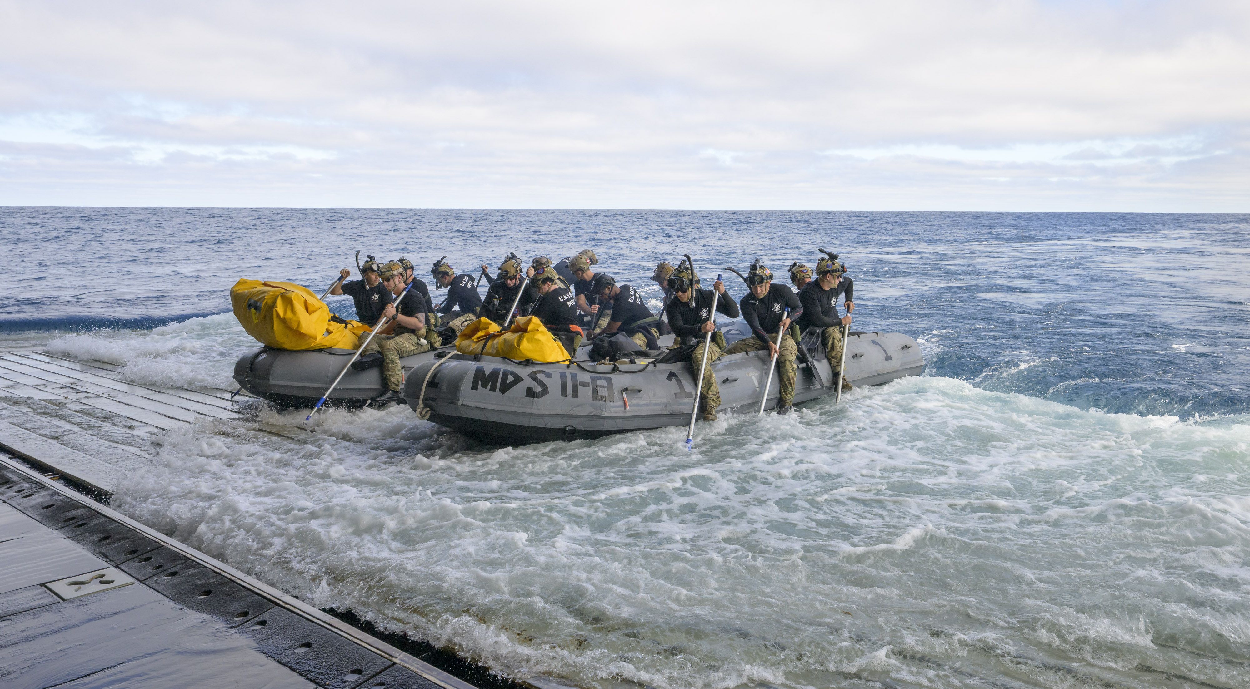 U.S. Navy divers prepare to deploy from the well deck of the USS John P. Murtha in small boats to recover Artemis II crew members