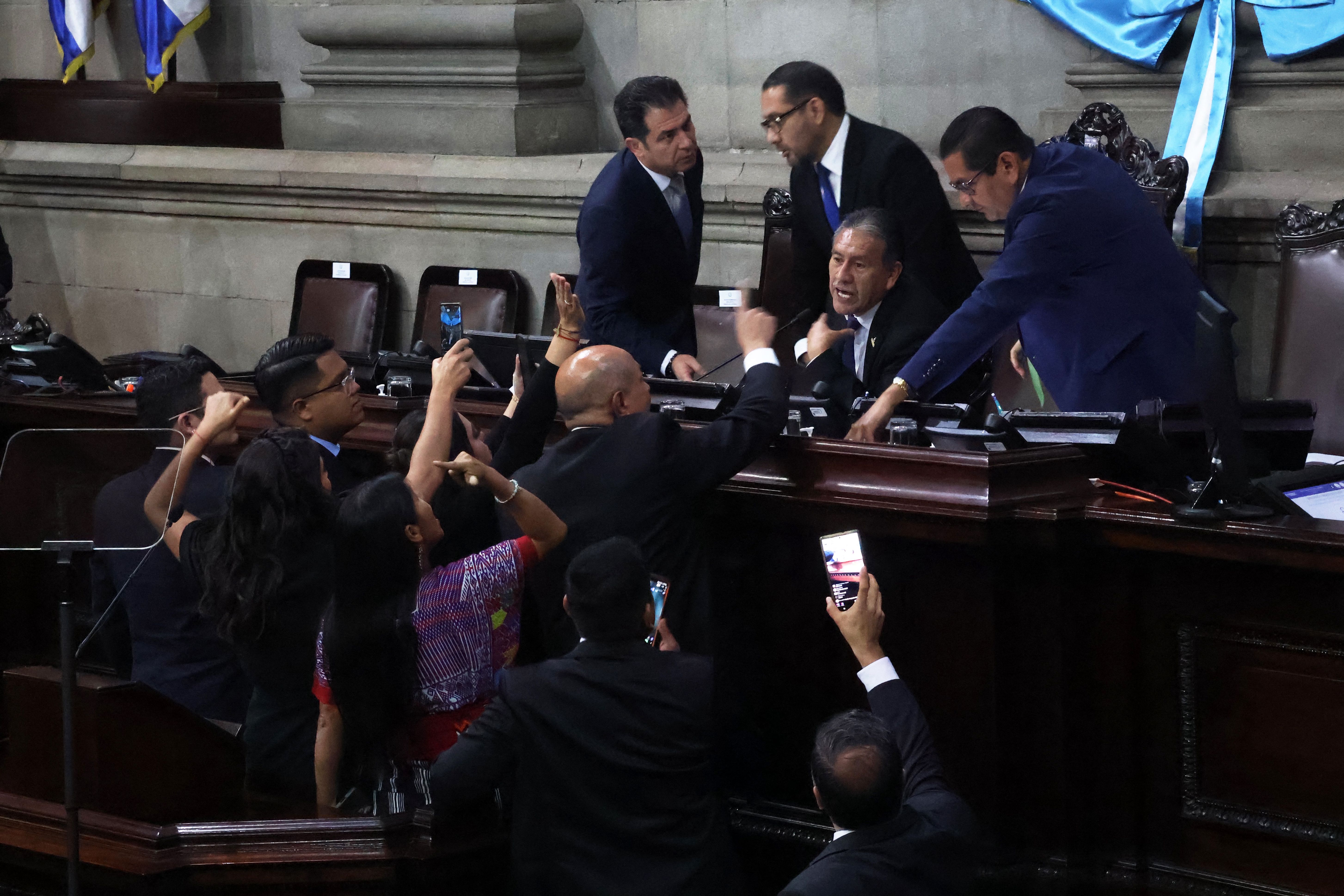 Guatemalan lawmakers wearing suits and dress clothes yell and point fingers at each other during a congressional session in which the swearing-in of President Arévalo.